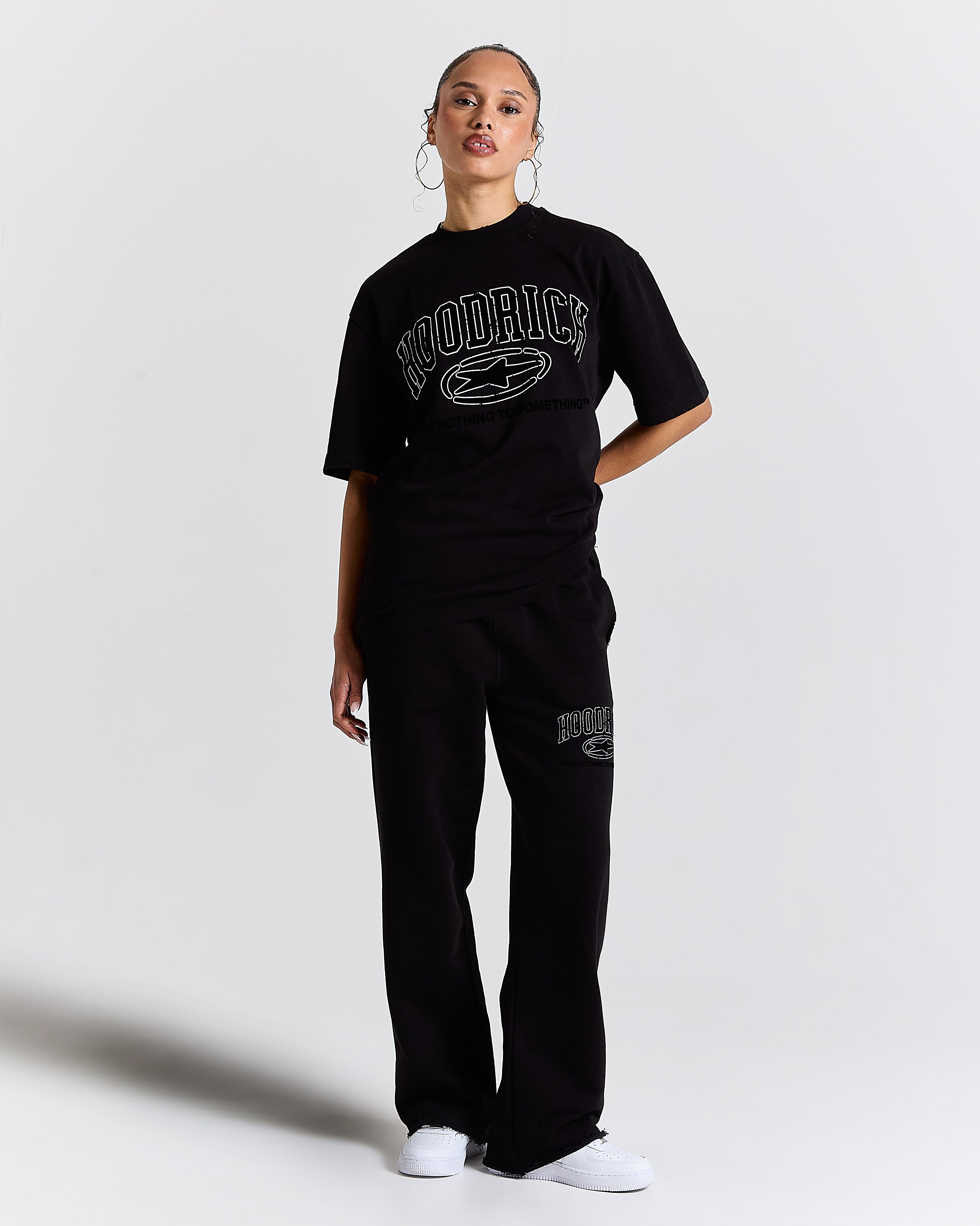 Person wearing a black 'Hoodrich' t-shirt and pants on a white background