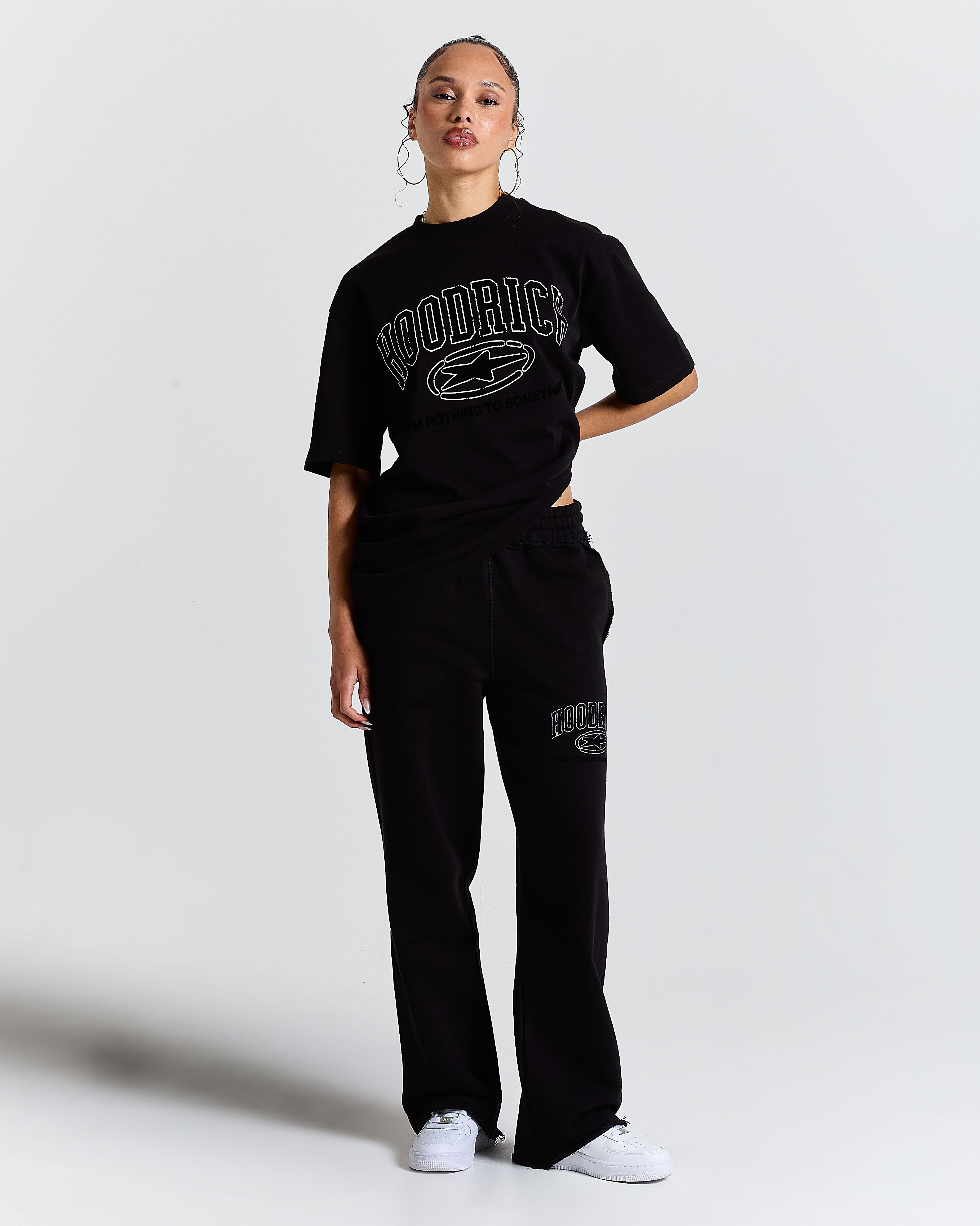 Person wearing a black 'Hoodrich' t-shirt and pants on a white background