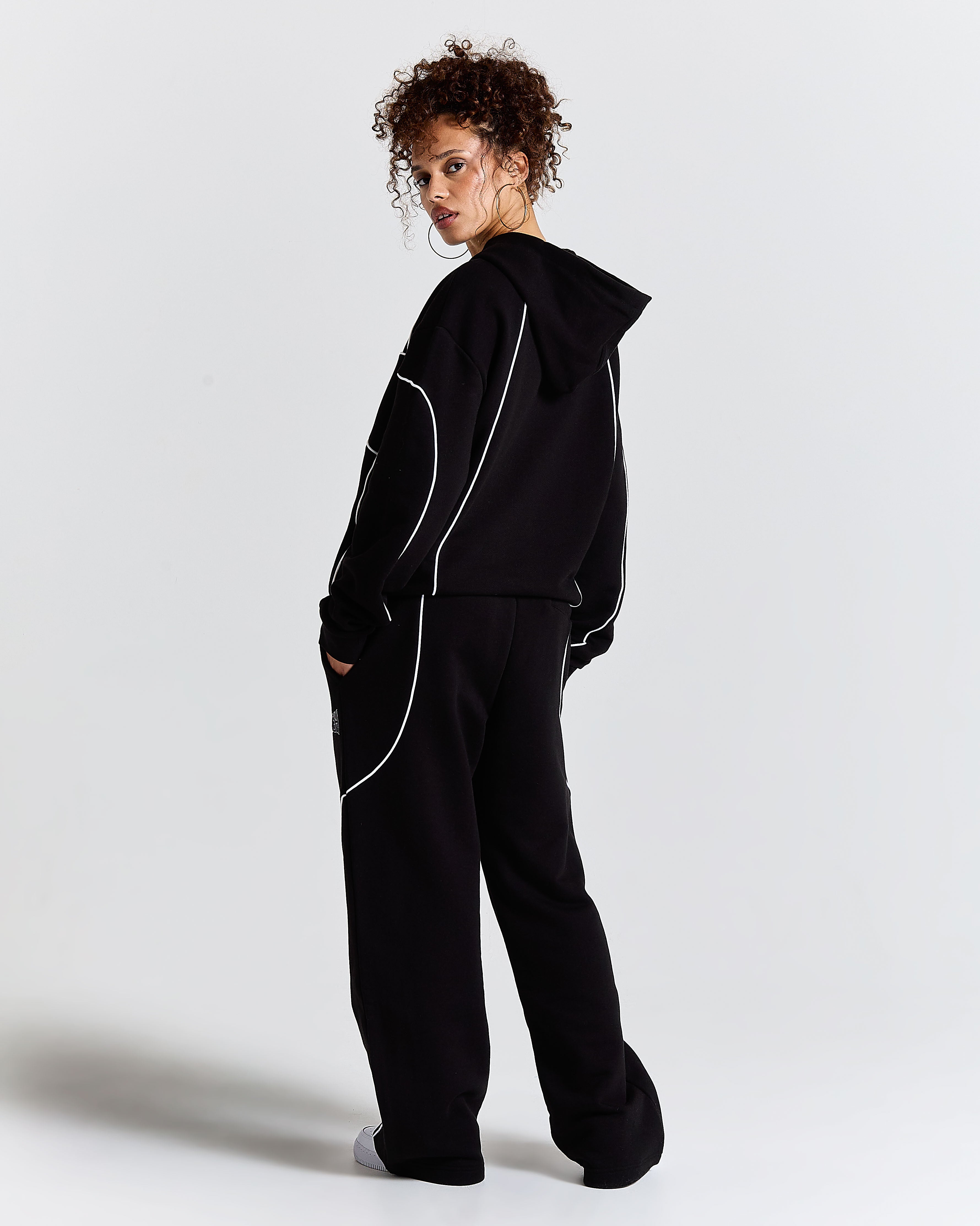 Person wearing a black tracksuit with white accents on a light gray background