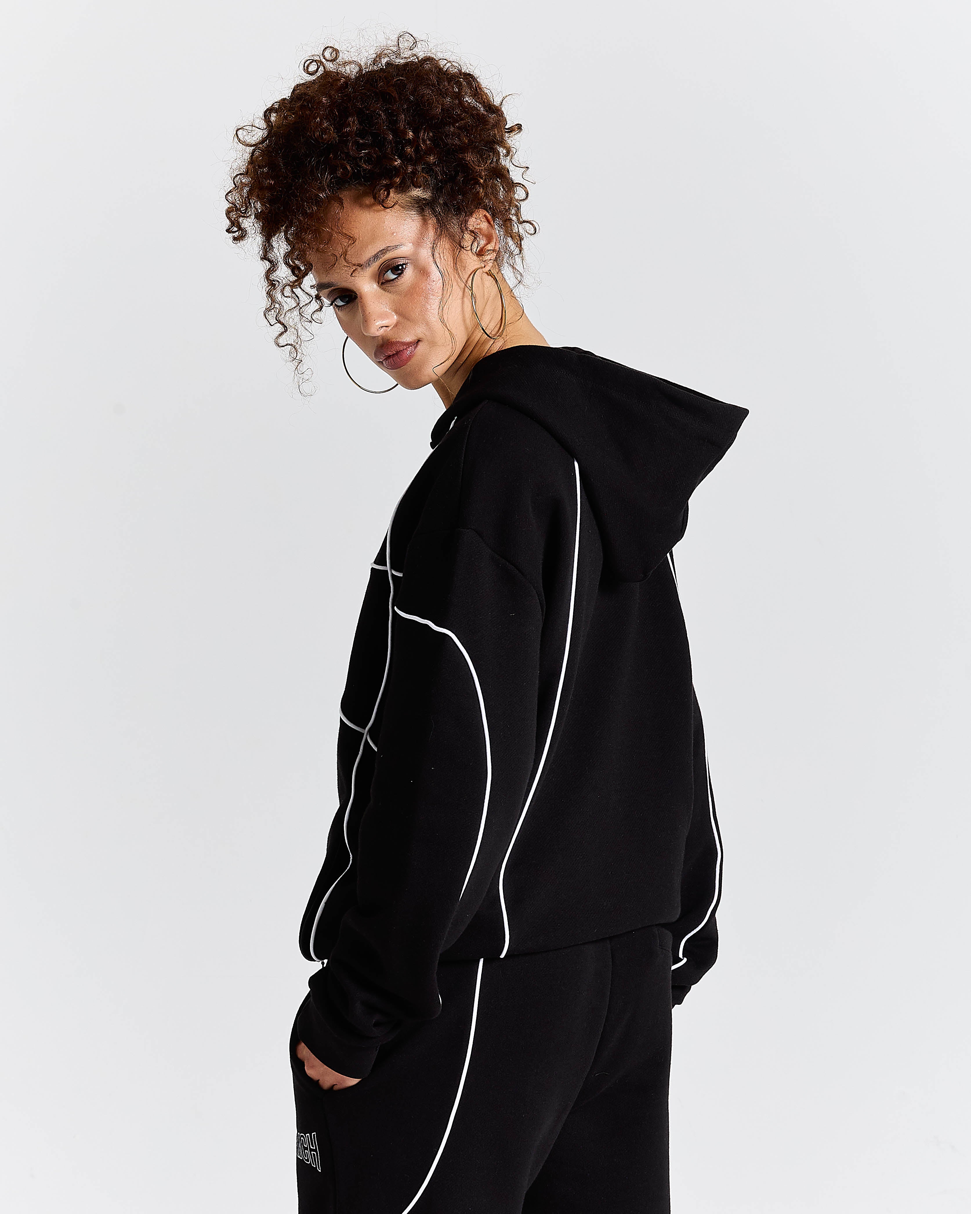 Person wearing a black hoodie with white accents on a light gray background