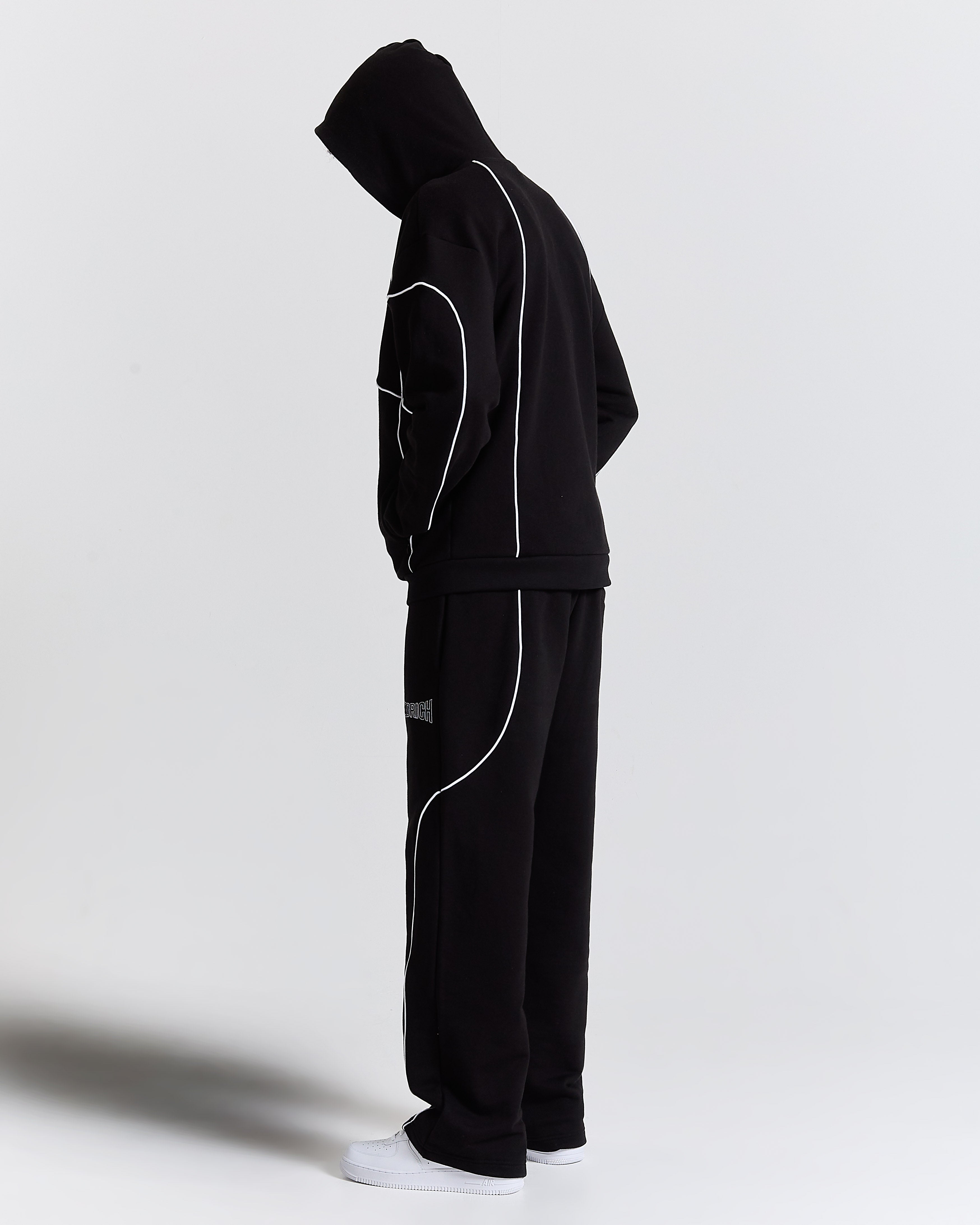 Black tracksuit with white piping on a light gray background