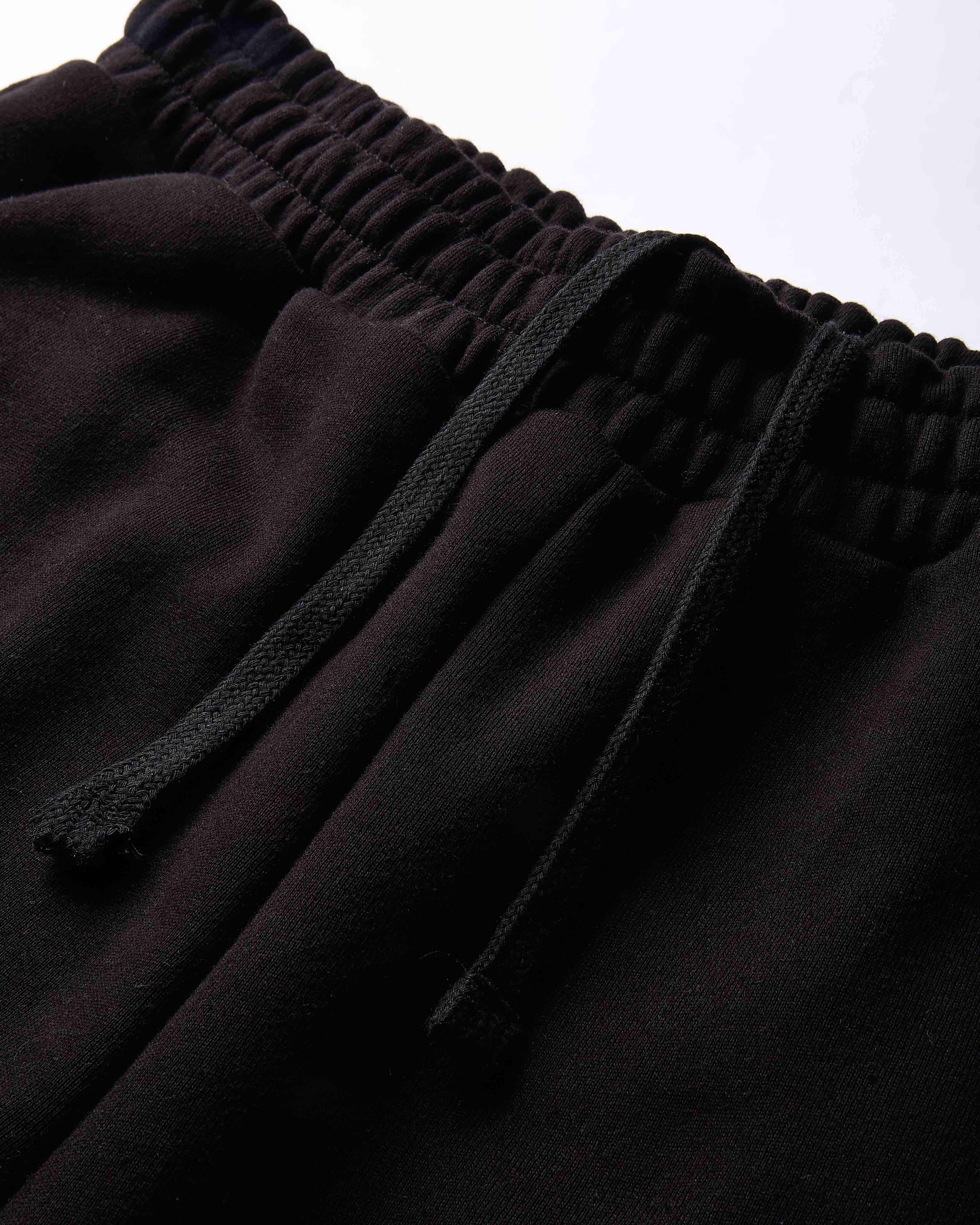 Close-up of black drawstring sweatpants showing the elastic waistband and fabric texture.