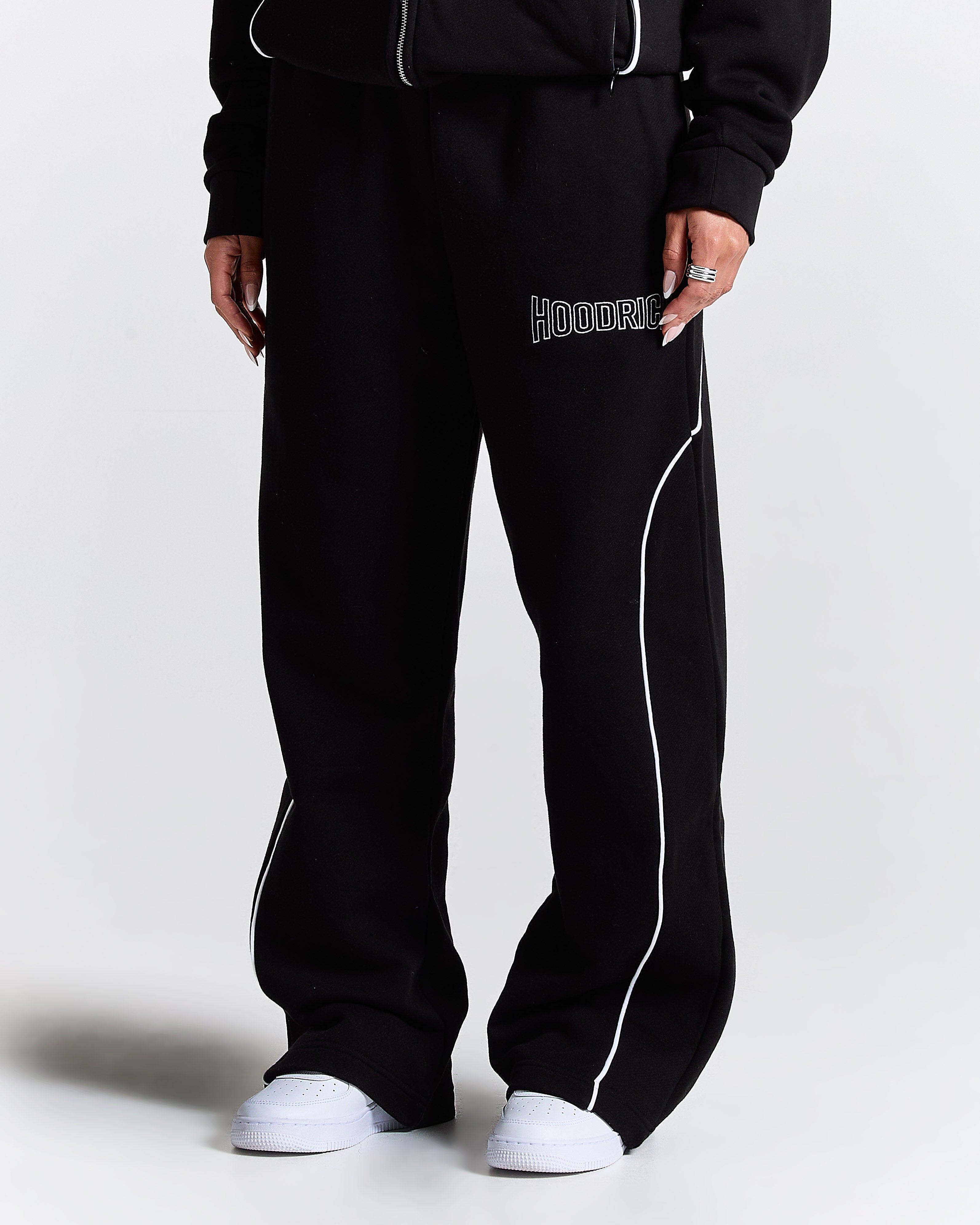 Black tracksuit with white piping on a plain background