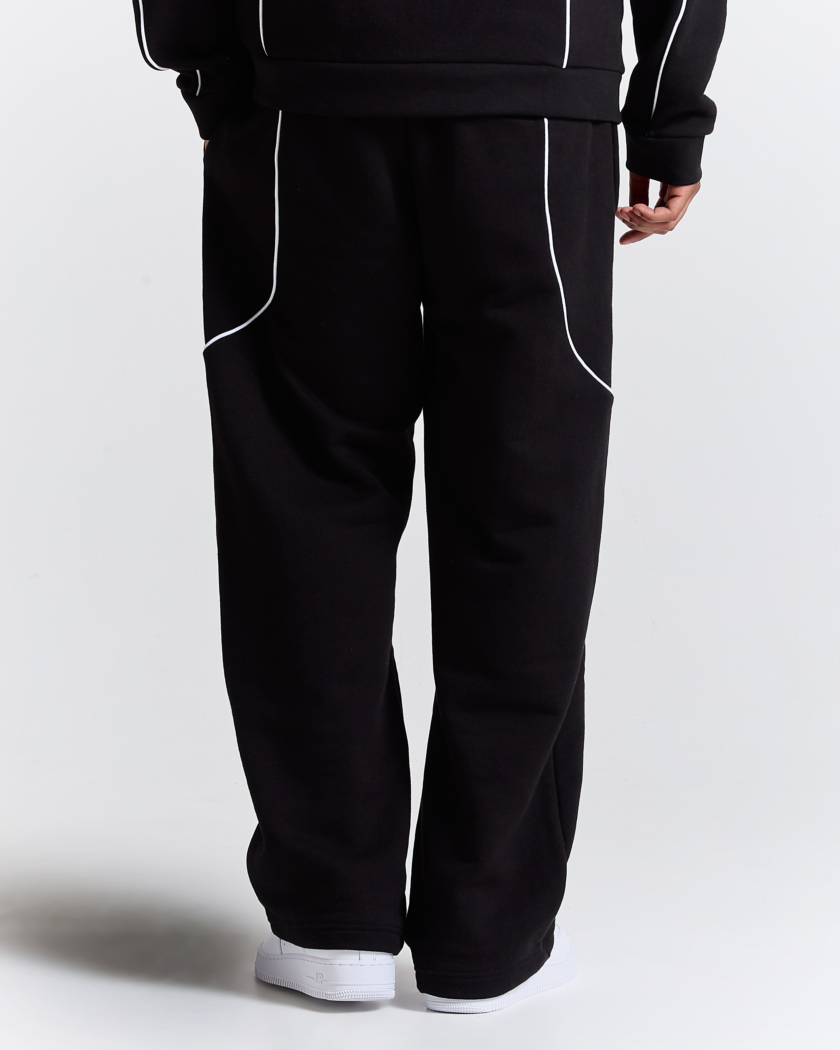 Black tracksuit with white piping on a plain background