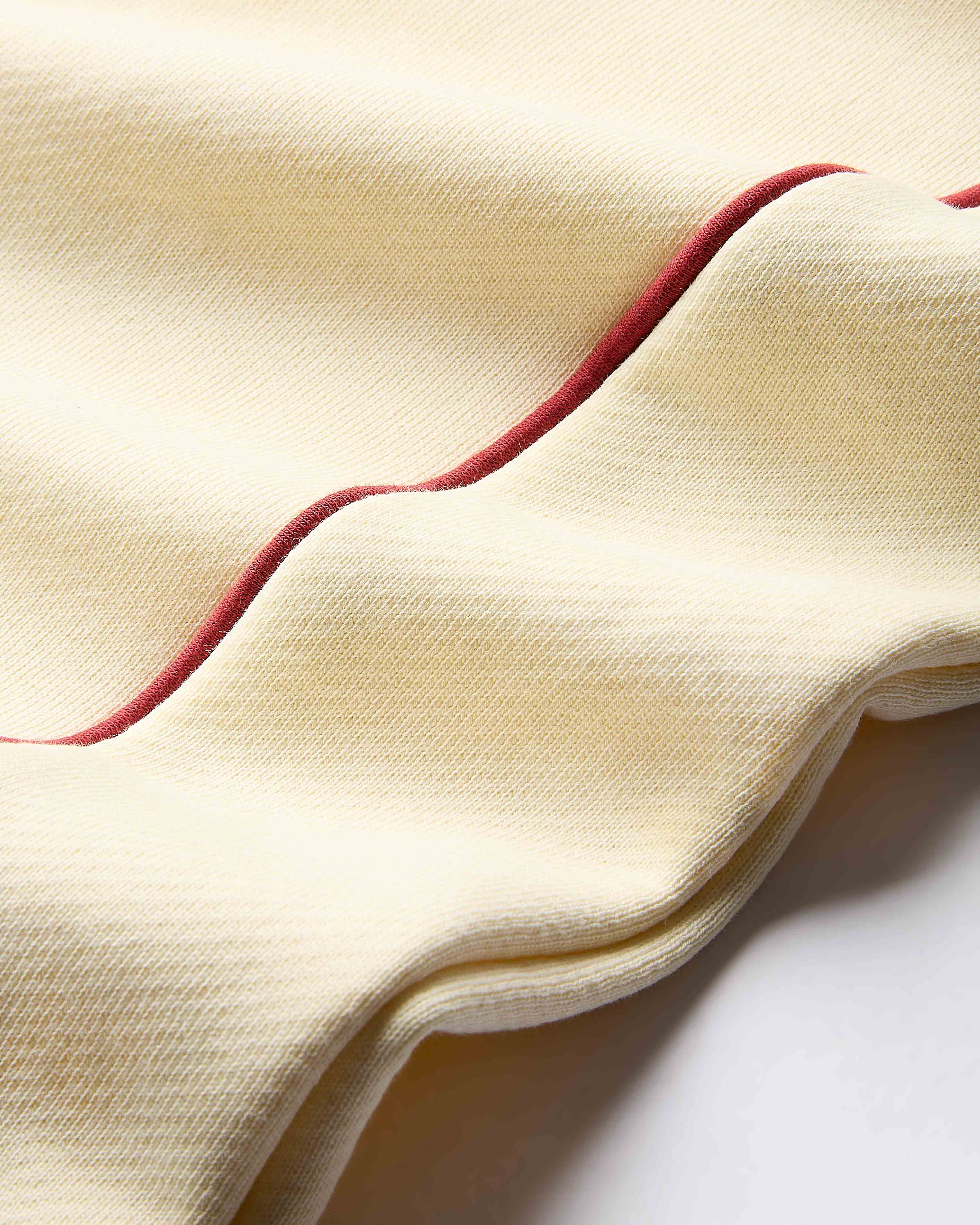 Close-up of beige fabric with red trim on a white background