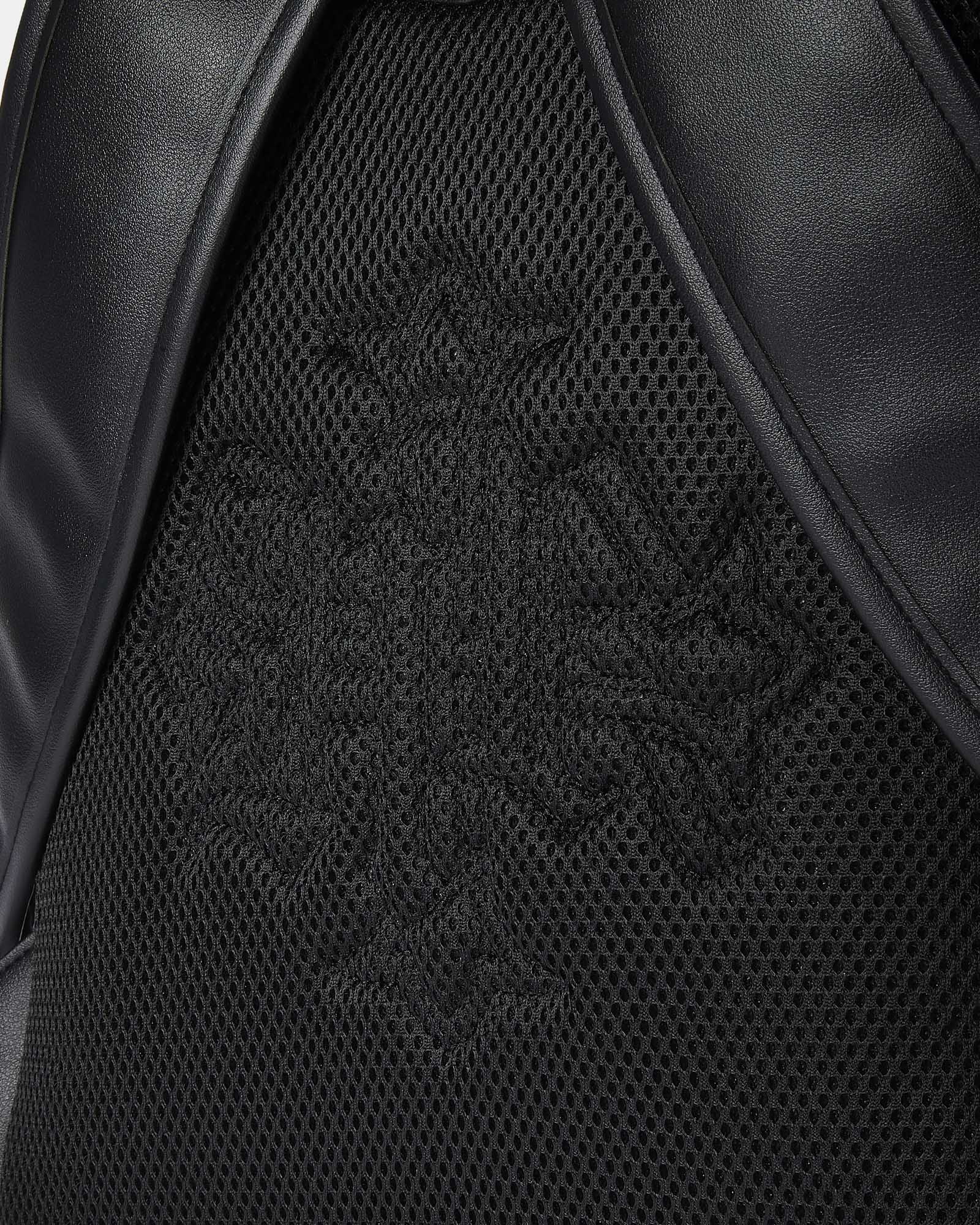 Close-up of a black leather product with a brand logo on a textured surface.