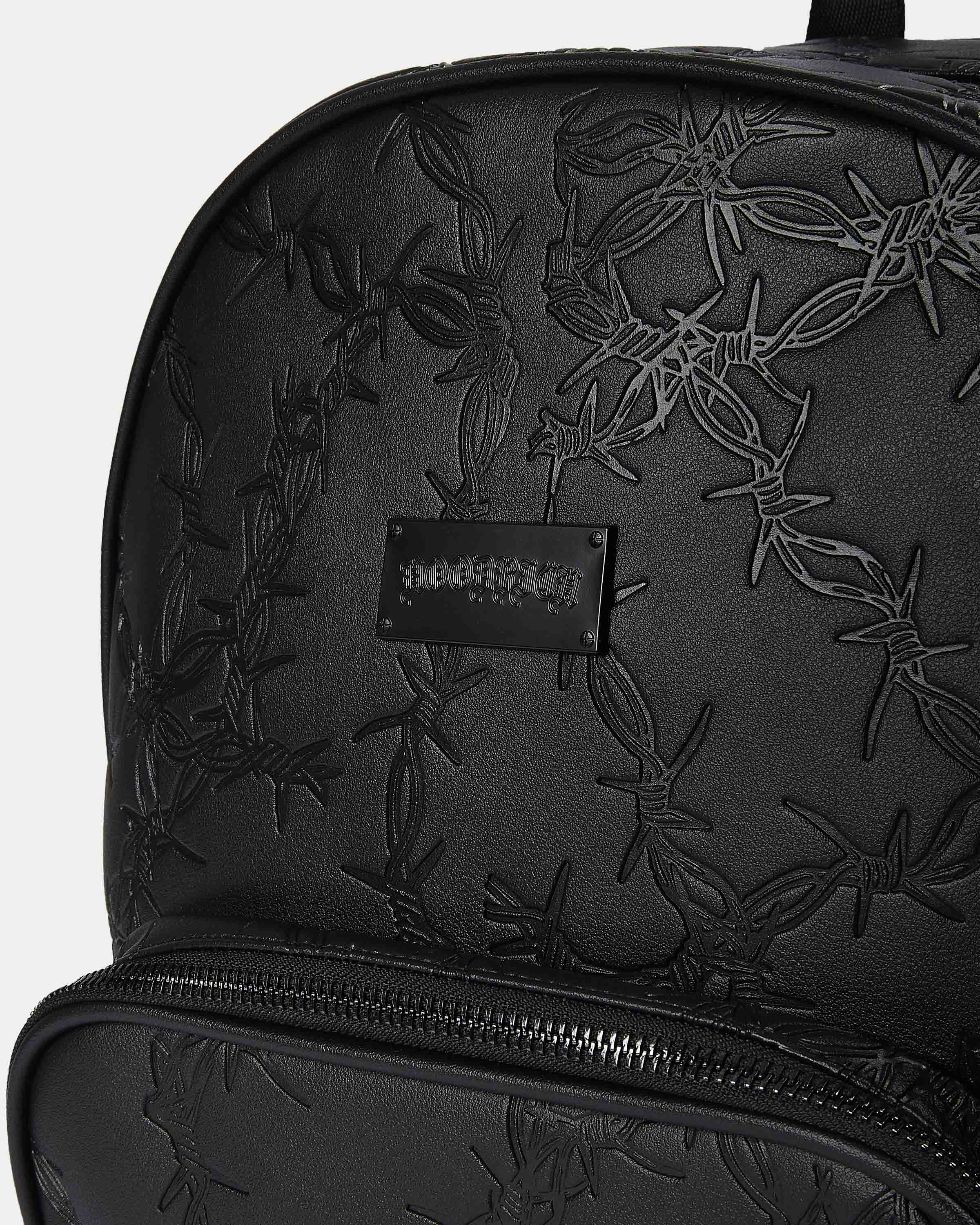 Black backpack with floral embossing and a visible brand logo on a white background