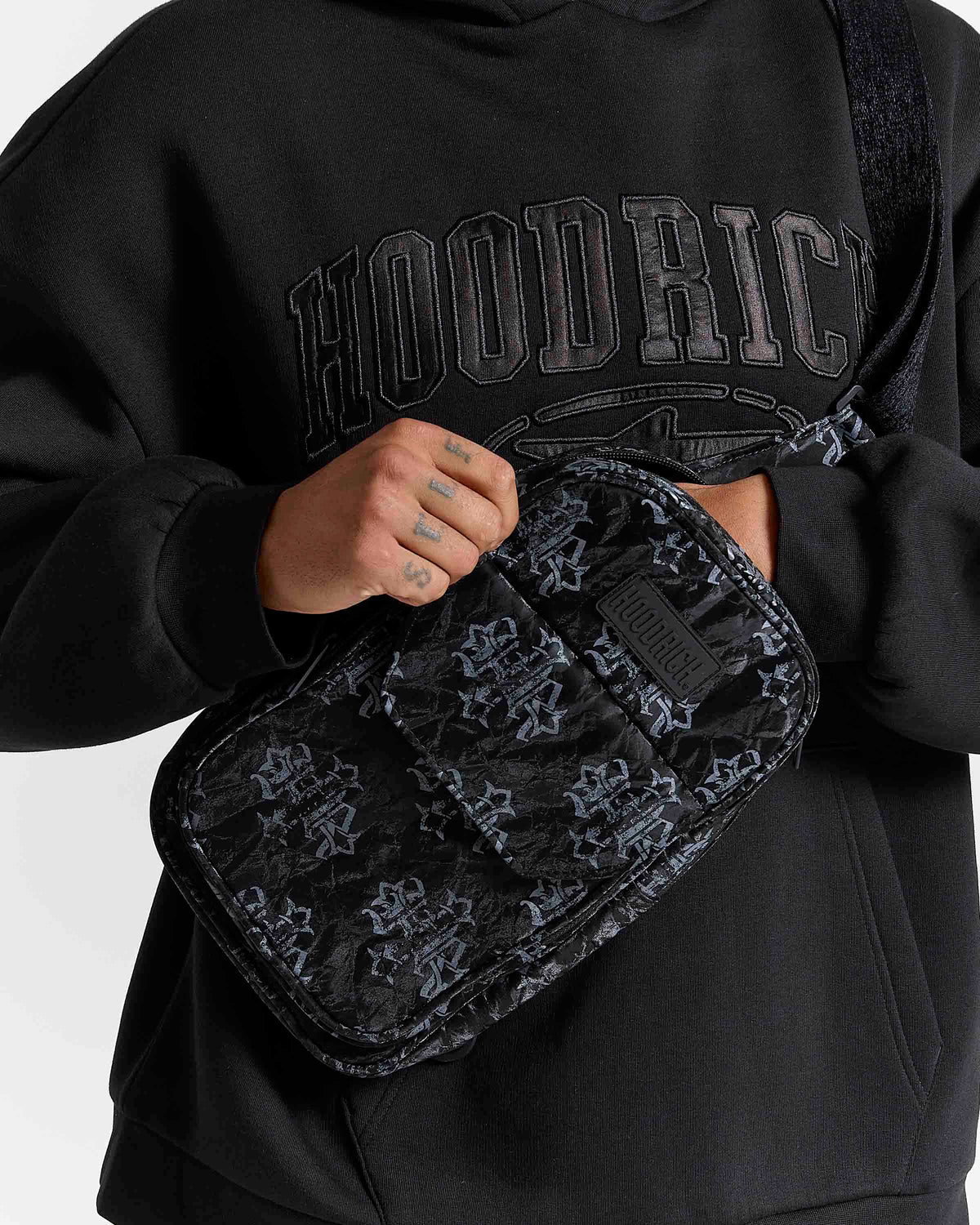 Displays a model wearing the Black & Grey 'Hoodrich' Virtux Sling Bag