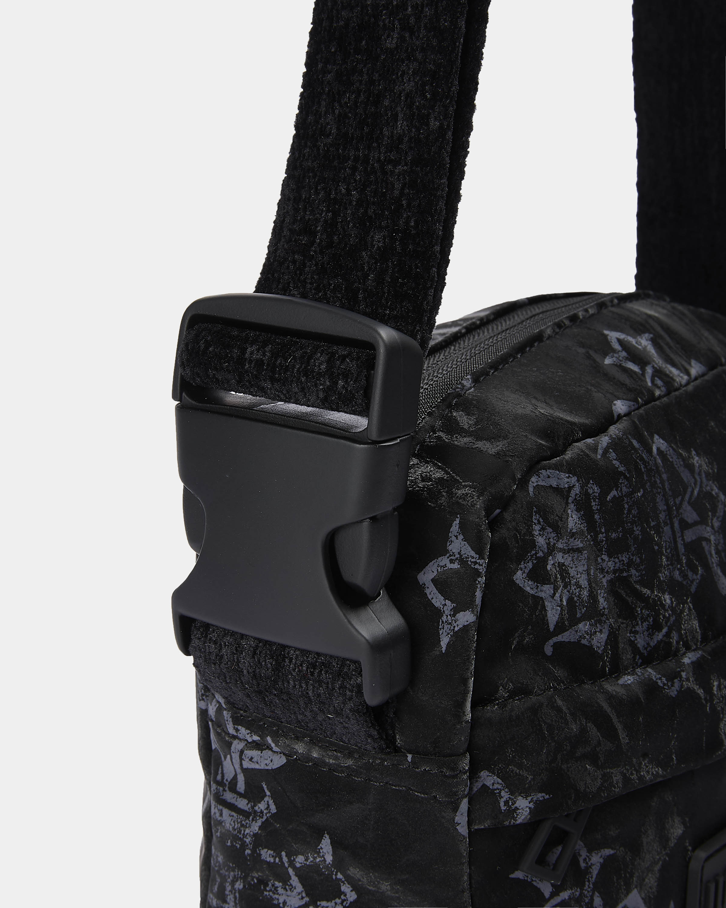 Close-up of a black patterned bag with a buckle on a light gray background