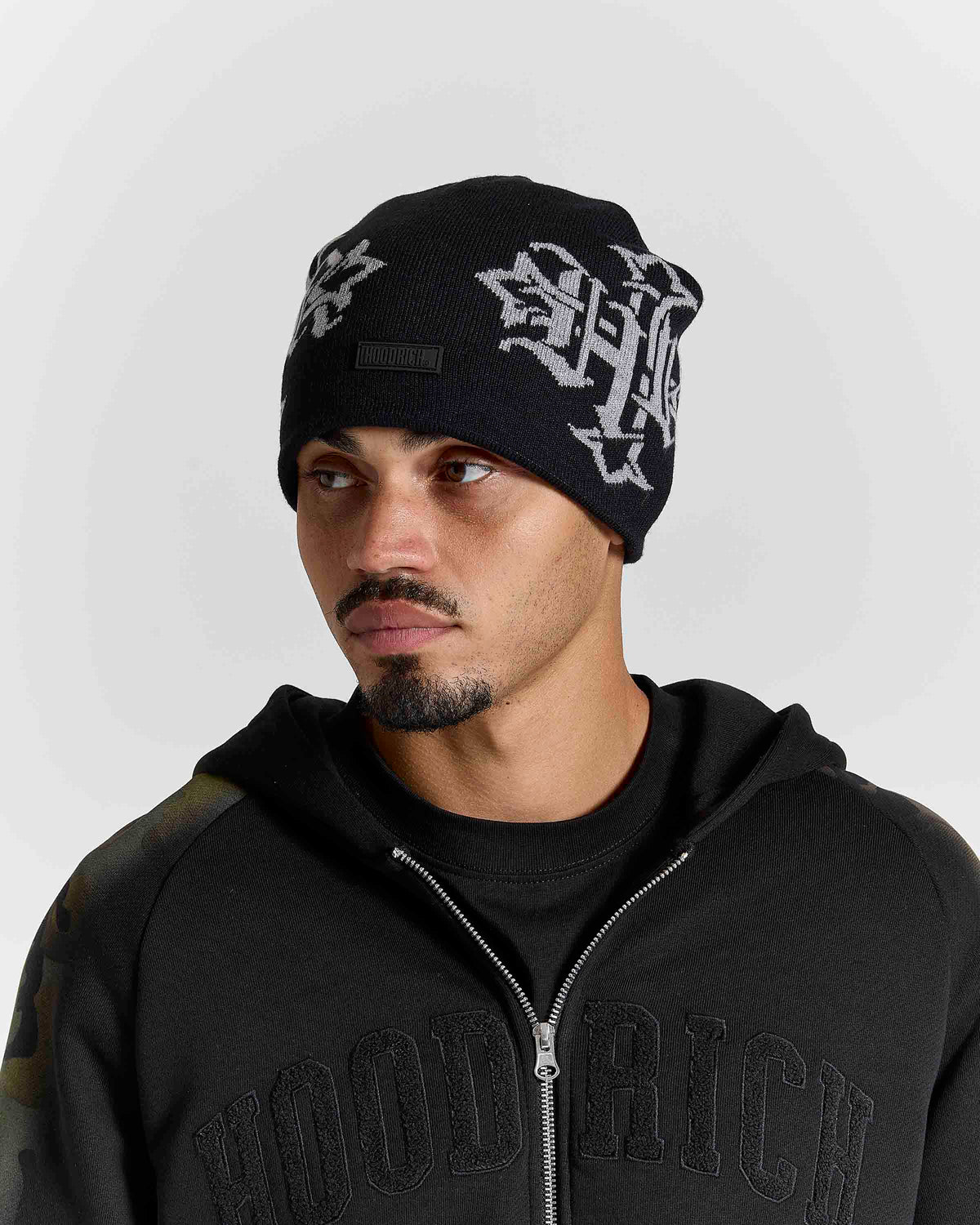 Displays a model wearing the Black & grey 'Hoodrich' branded Virtux Skull Knit Beanie