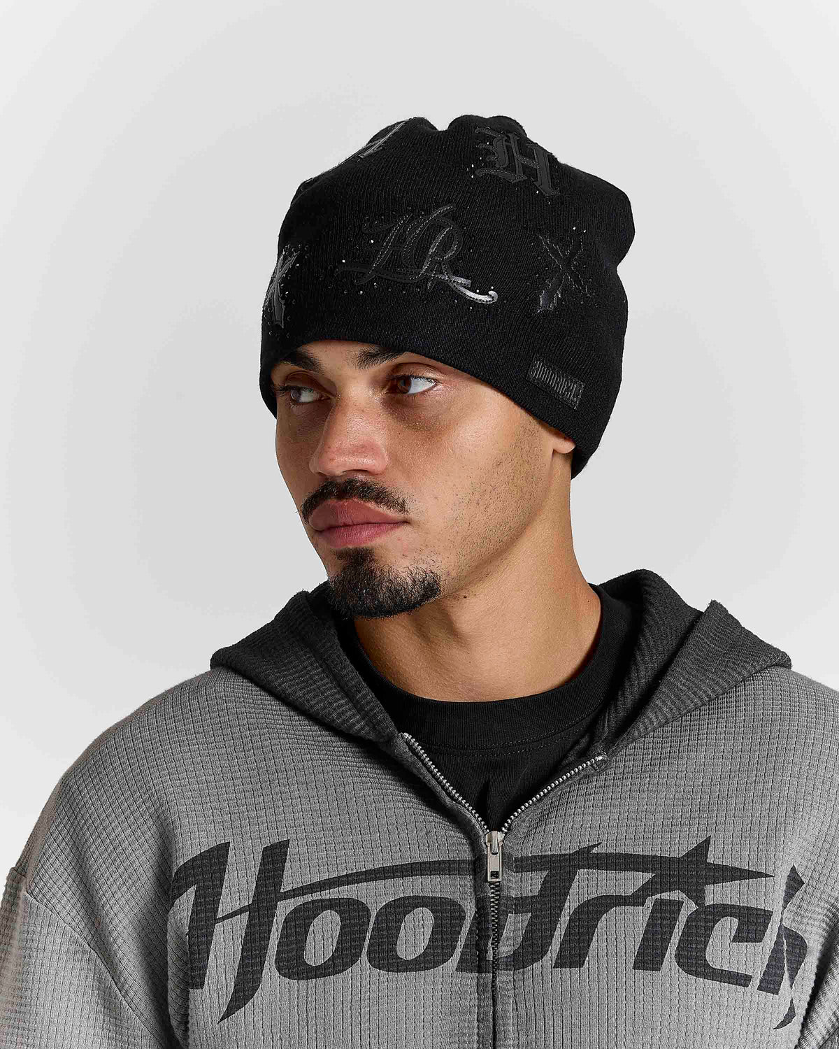 Displays a model wearing the black 'hoodrich' branded Scar Knitted Fitted Beanie 