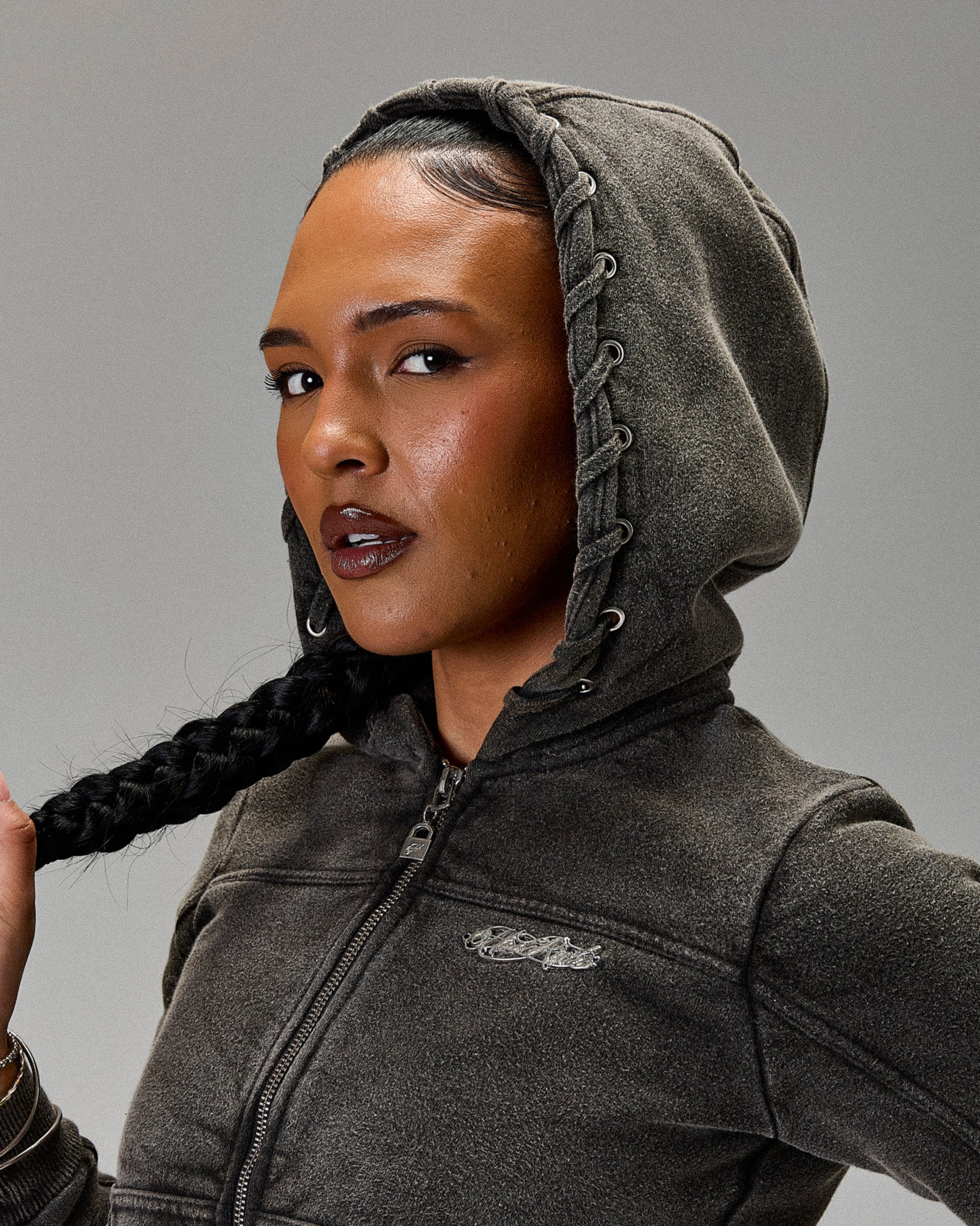 Person wearing a gray hoodie with a brand logo on a gray background