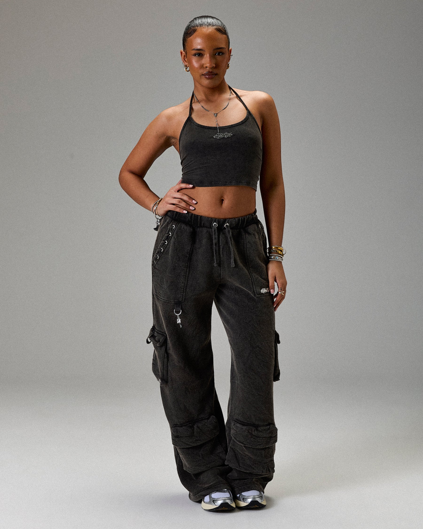 Woman wearing a black crop top and cargo pants on a gray background