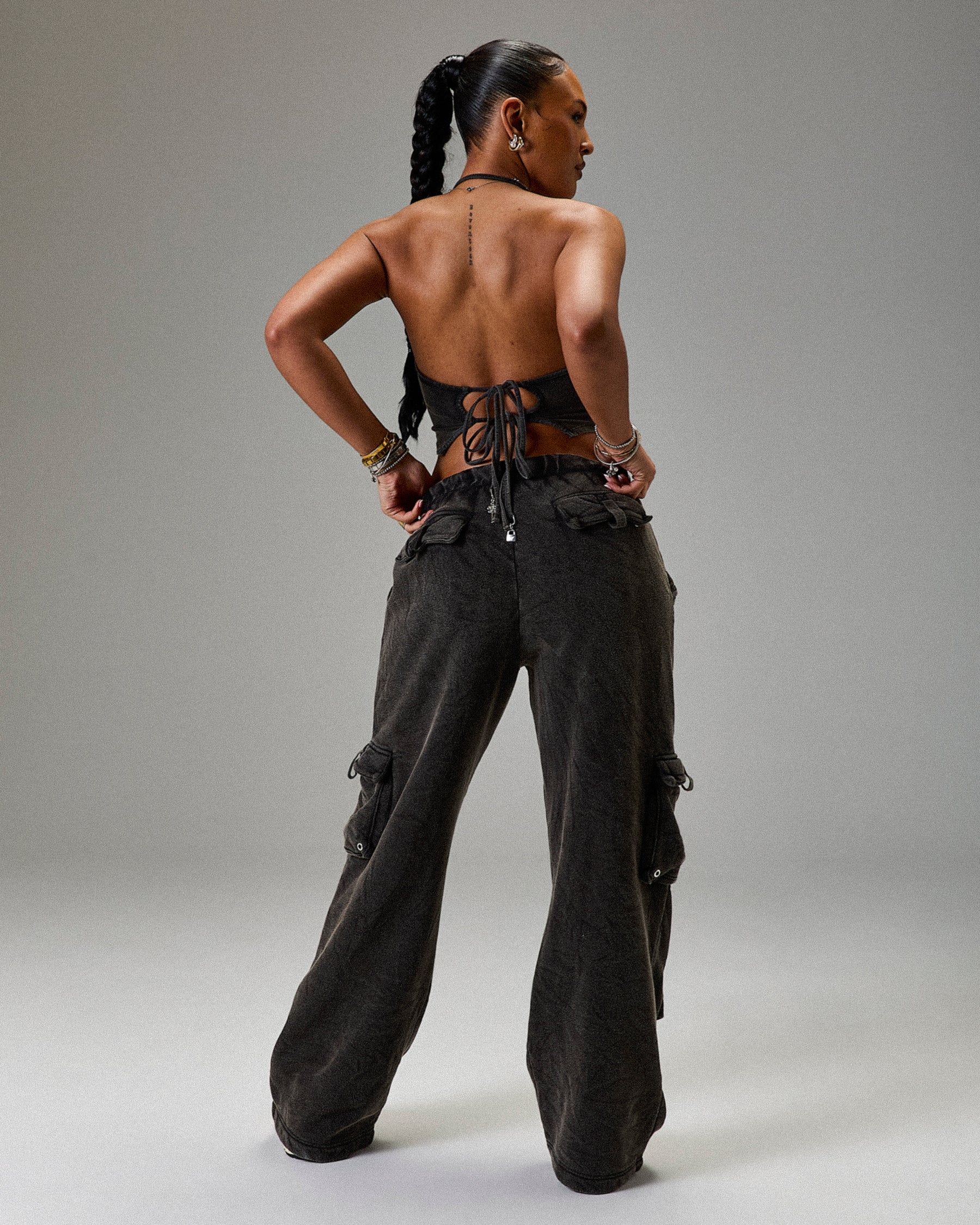 Person wearing a black lace-up top and wide-leg pants on a gray background