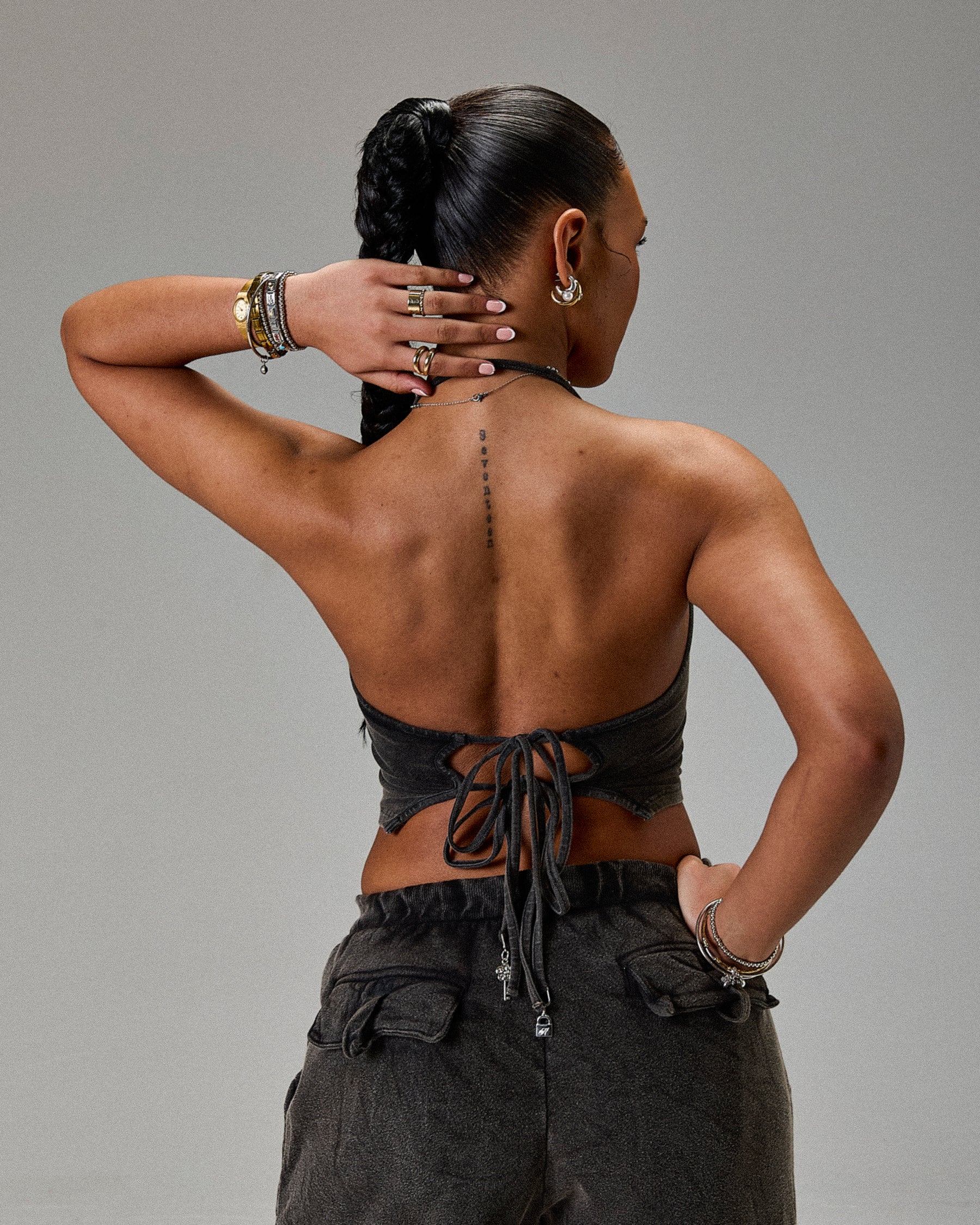 Person wearing a black strapless top and dark pants against a gray background