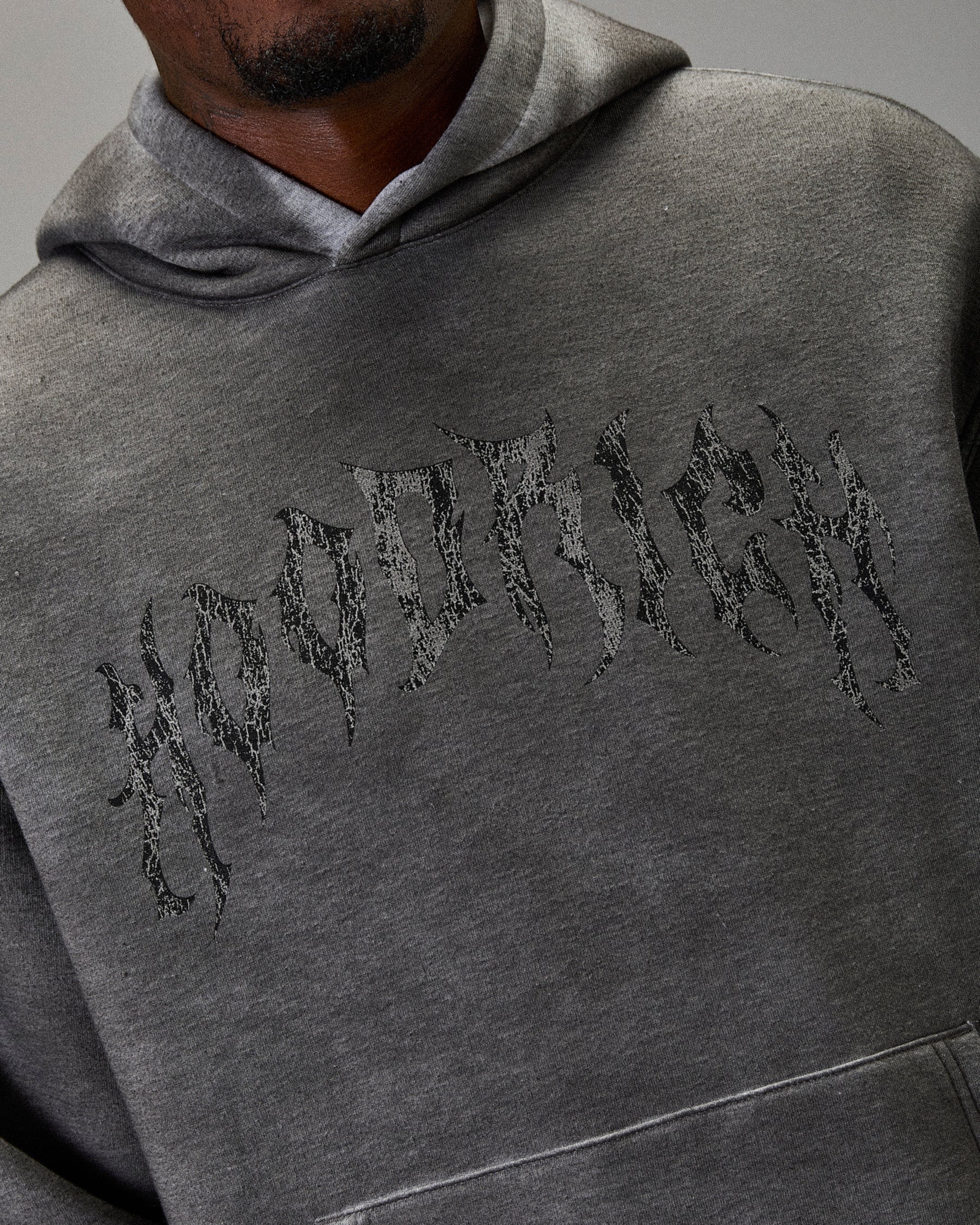 Gray hoodie with embroidered text on a gray background. Hoodie says "Hoodrich"