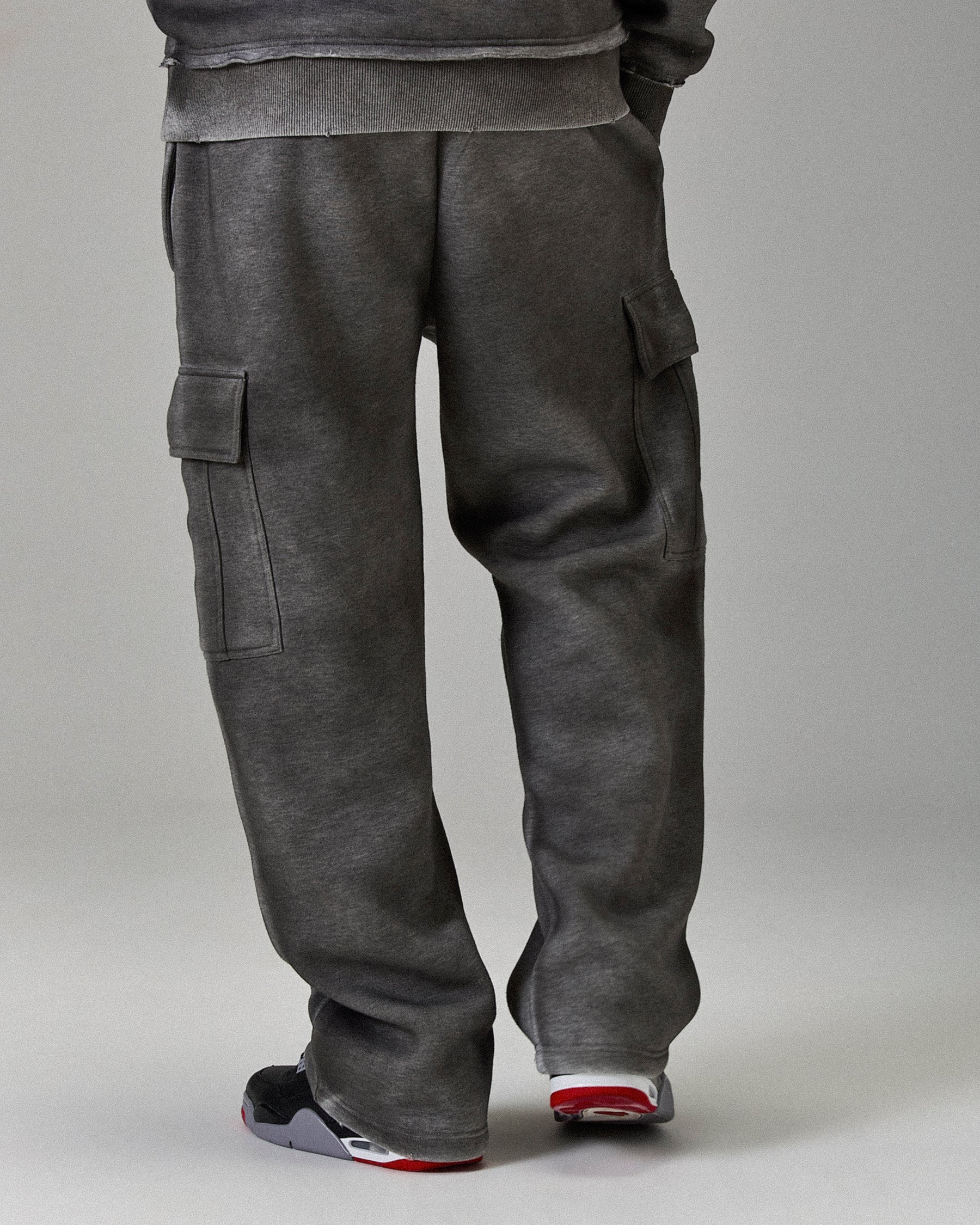 Person wearing gray cargo pants on a plain background