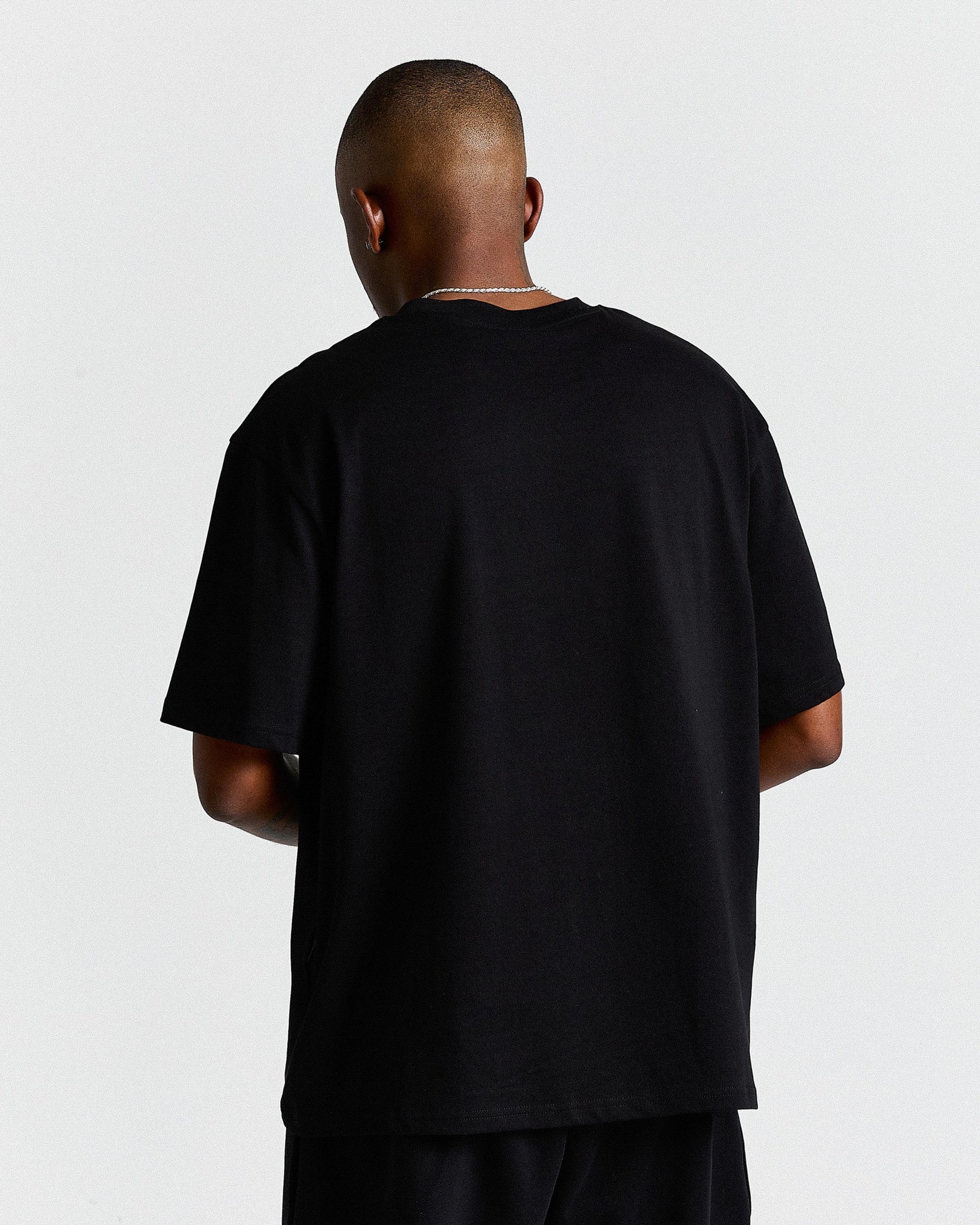 Person wearing a black t-shirt on a plain background