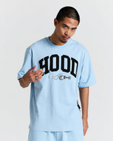 Person wearing a light blue t-shirt with 'HOODRICH' text on a plain background