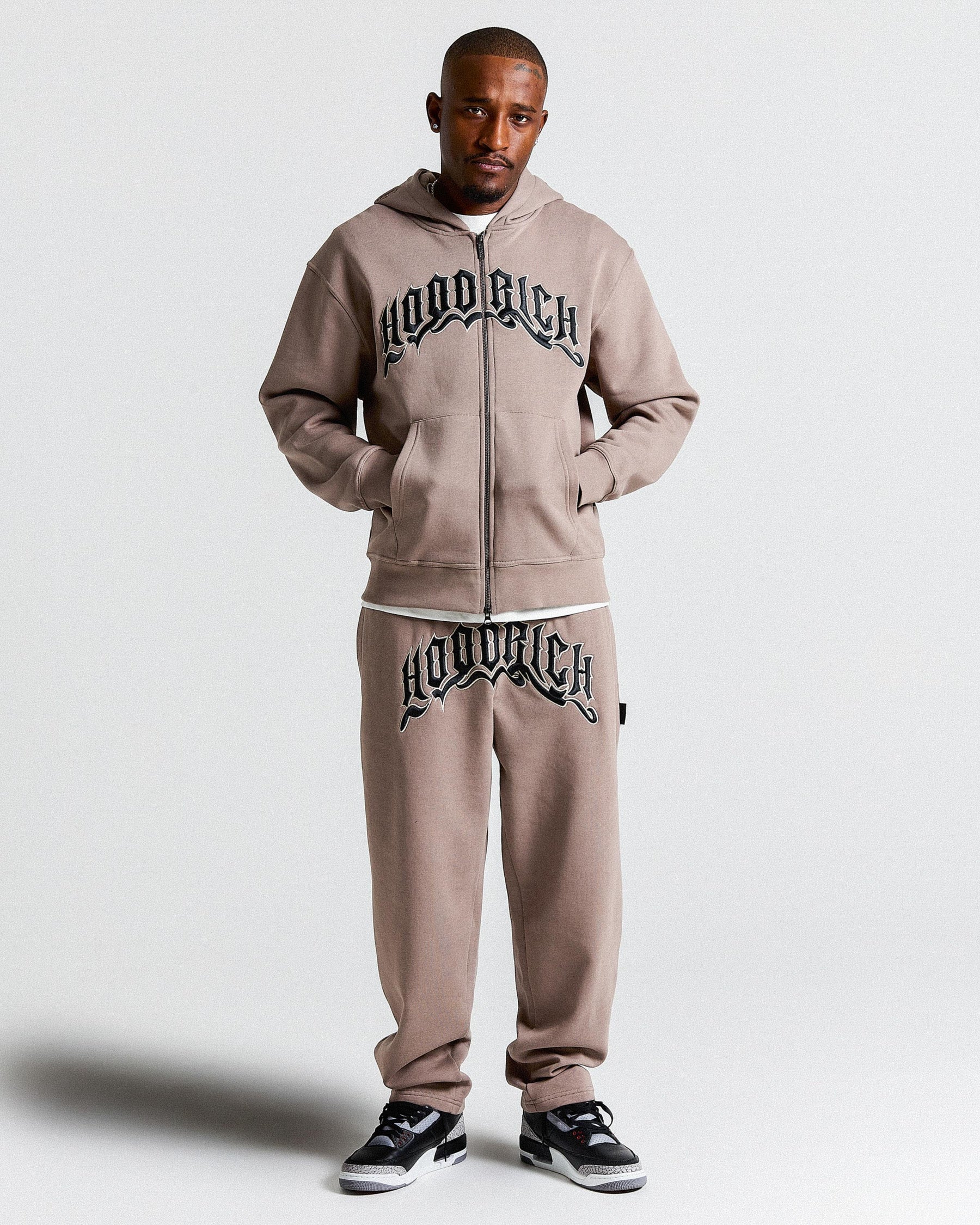 Man wearing a 'HOODRICH' tracksuit on a white background.