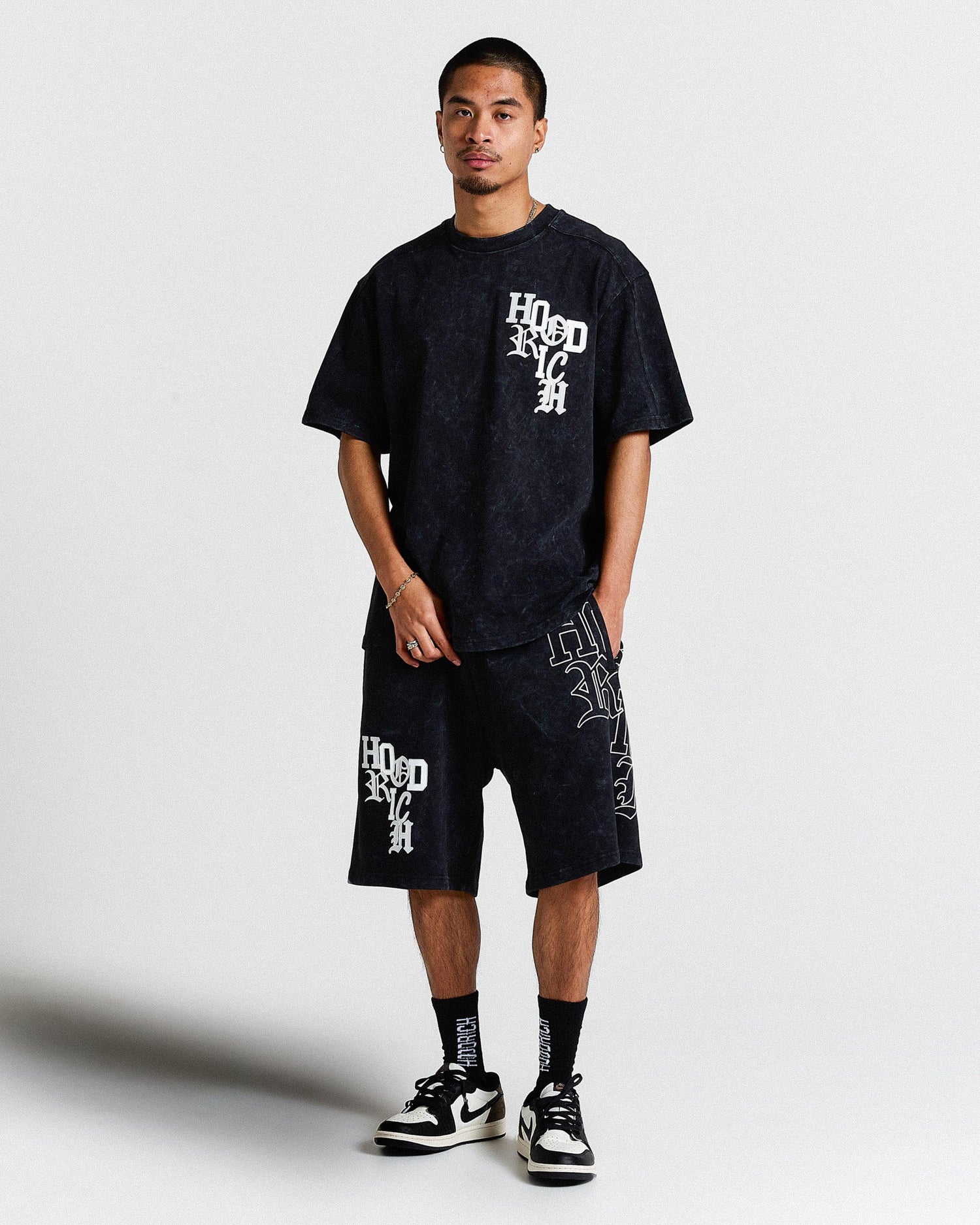 Person wearing a black t-shirt and shorts with white text on a light gray background