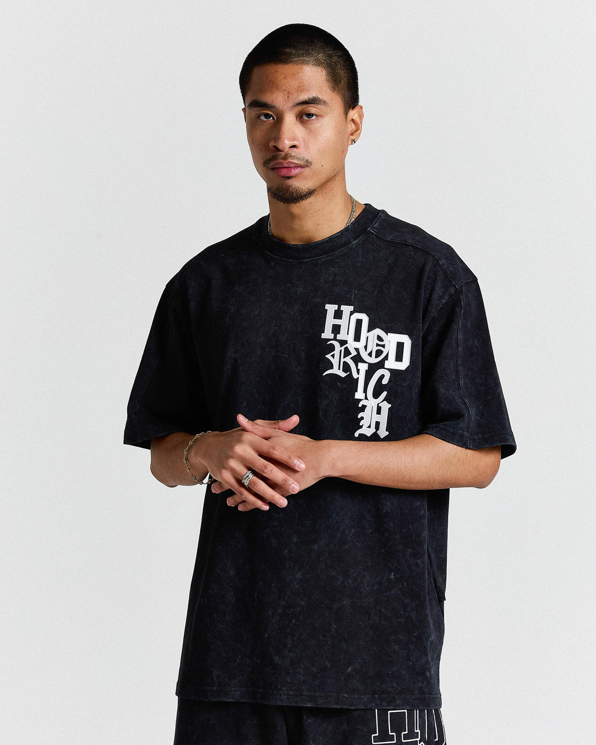 Person wearing a black t-shirt with 'Hood Rich' text on a plain background