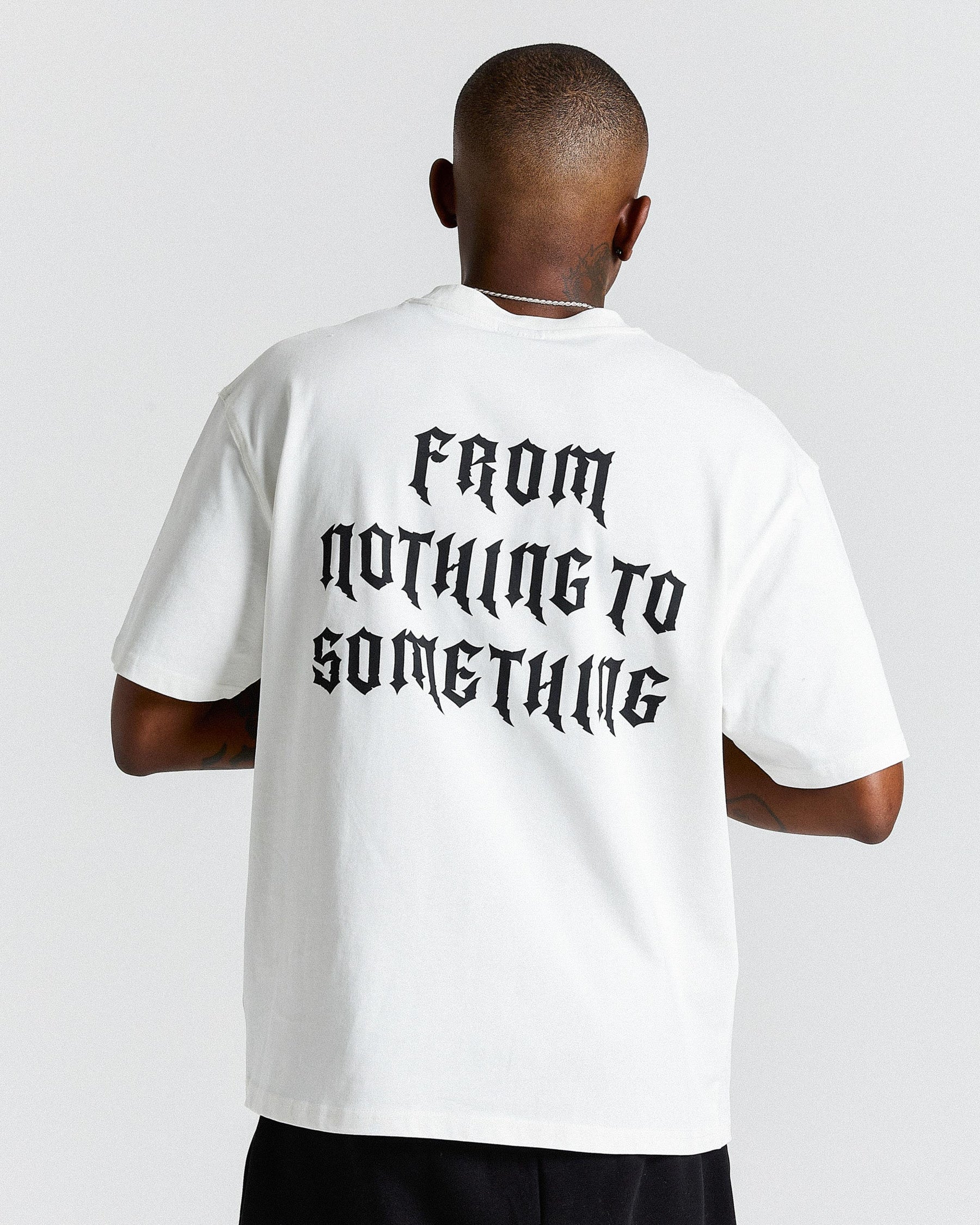 Person wearing a white t-shirt with 'From Nothing to Something' text on the back, standing against a plain background.
