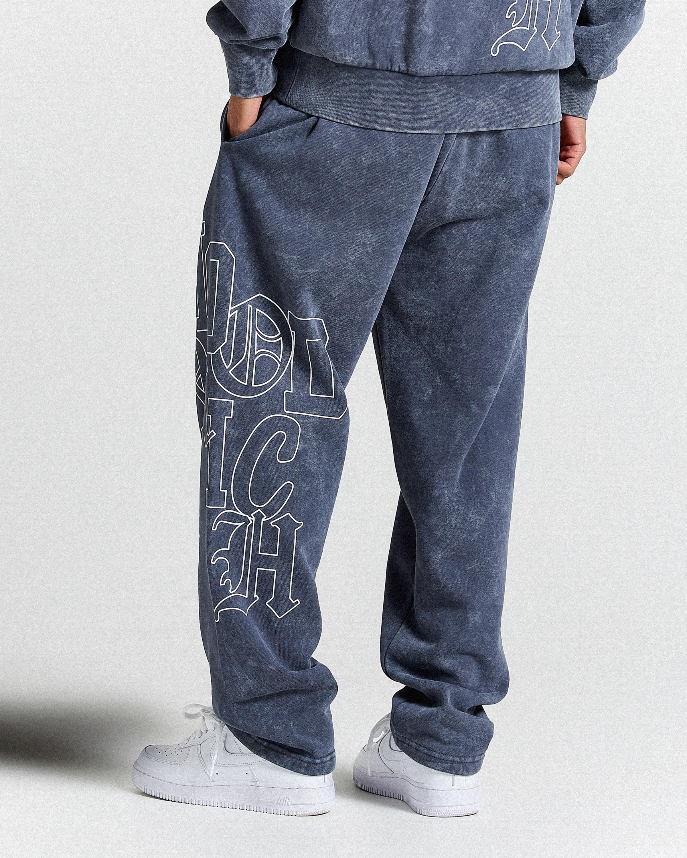 Person wearing blue sweatpants with white text on a plain background