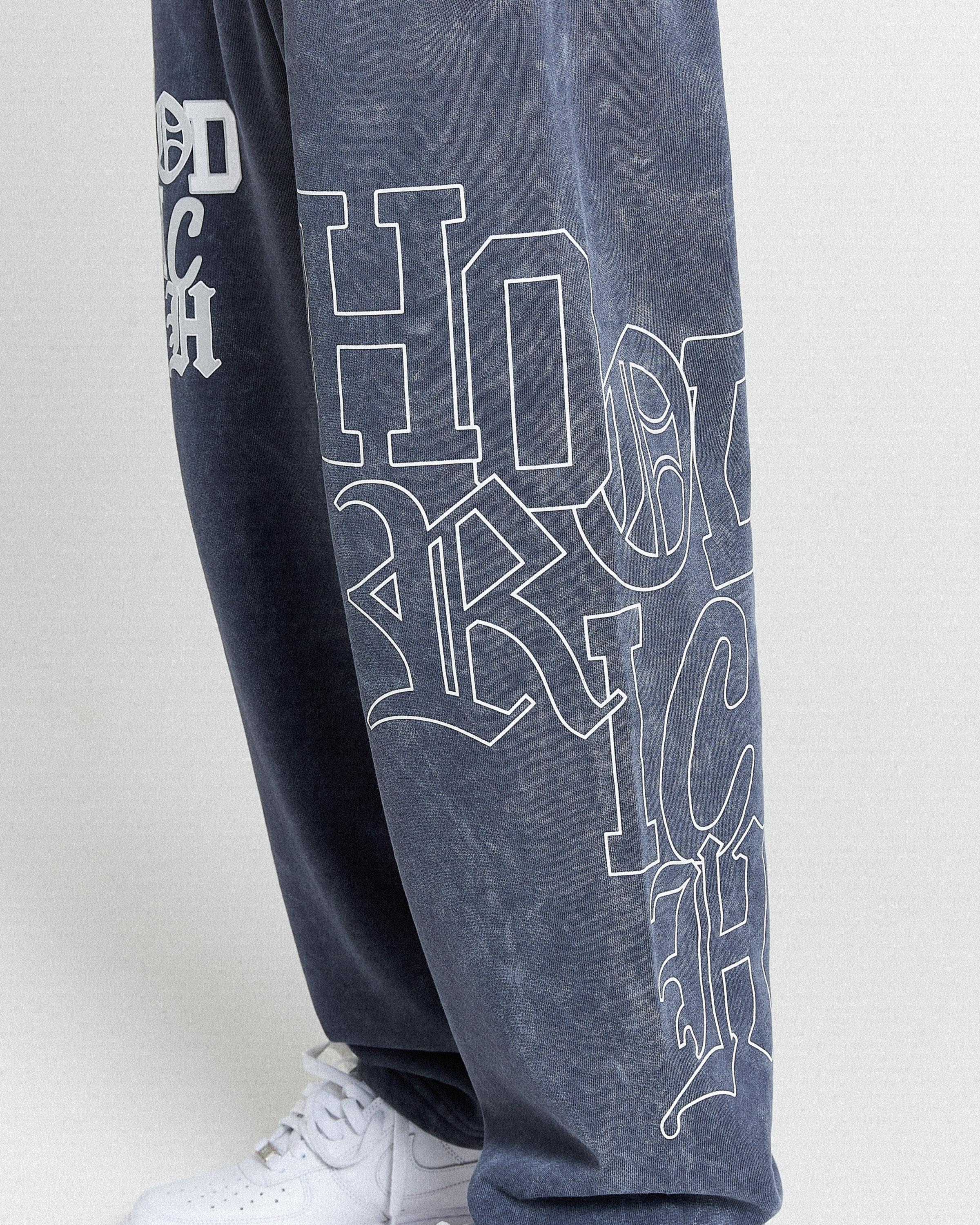 Navy blue sweatpants with white text on a light gray background