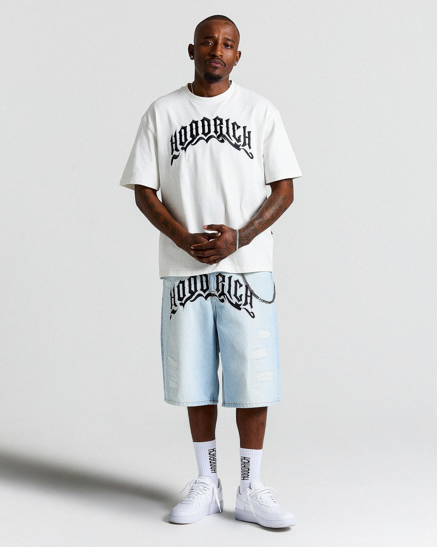 Person wearing a white t-shirt and light blue shorts with 'Hoodrich' branding on a plain background