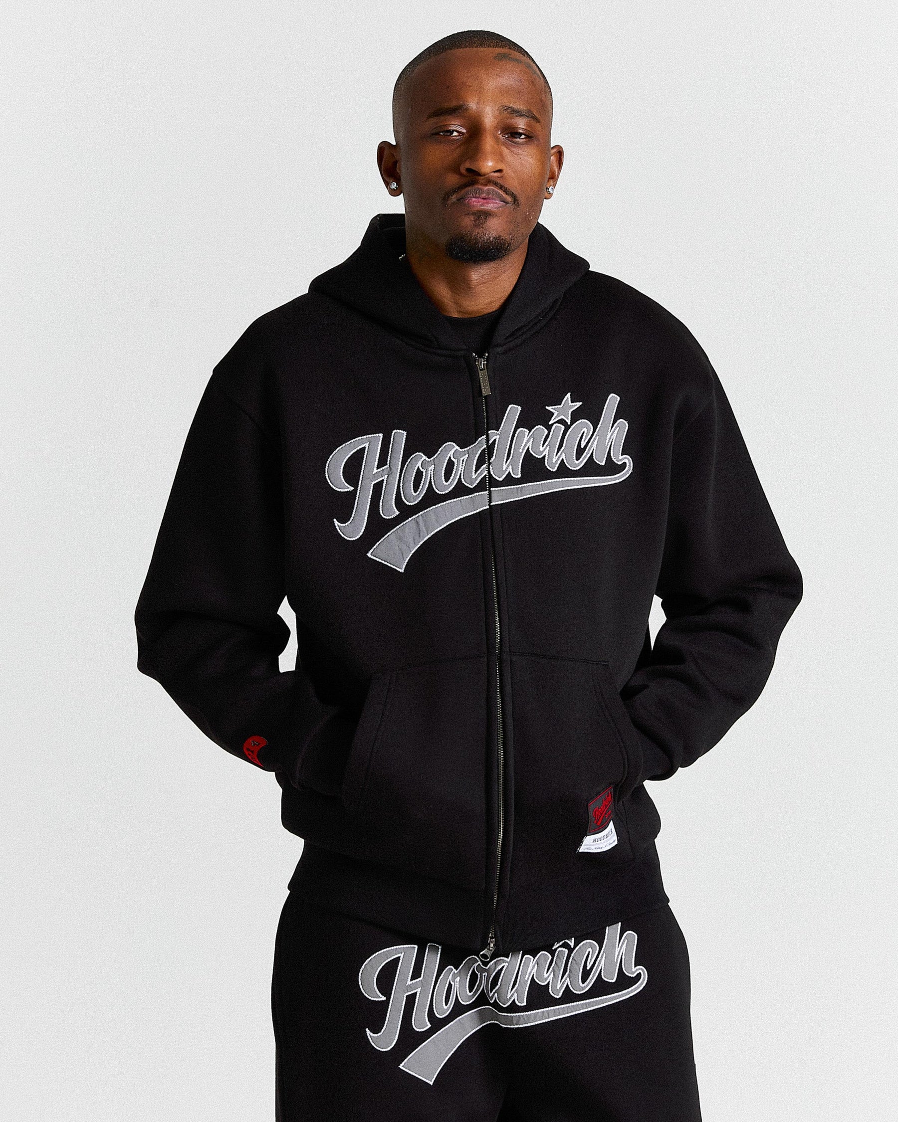 Man wearing a black hoodie with 'Hoodrich' branding on a white background