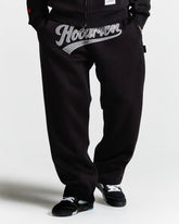 Black pants with 'Hoodrich' logo worn by a person on a white background