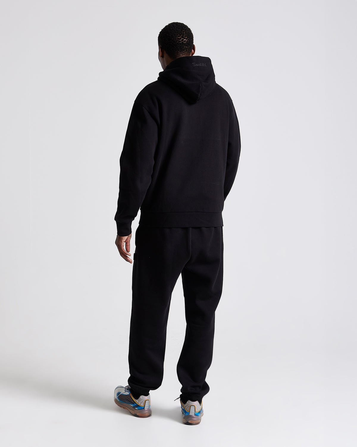 Displays a model wearing the Black 'Hoodrich' branded men's Curve Full Tracksuit 