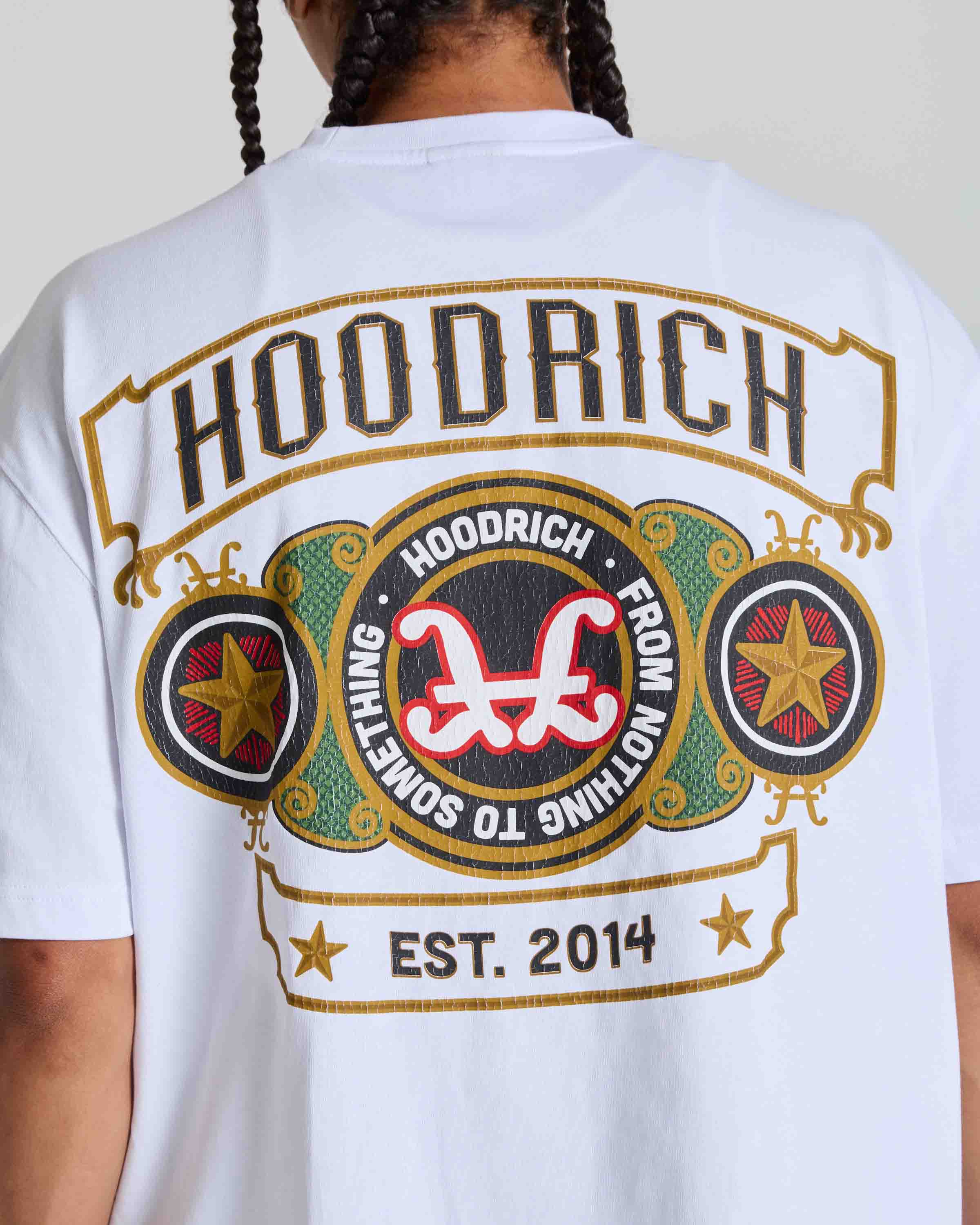 A person shown from the back wearing a white graphic T-shirt with a large multicolor 'HOODRICH' logo print on the back.