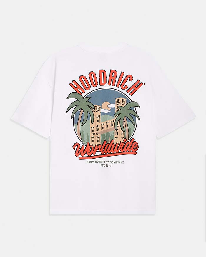 A white short-sleeve t-shirt shown from the back, featuring a large graphic print with the brand name 'HOODRICH' in red arched letters above a retro illustration of a building and palm trees, and 'Worldwide' in red script below.