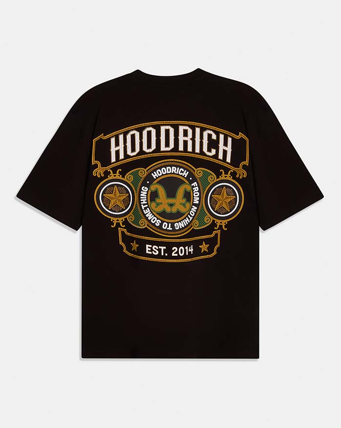 A black short-sleeve t-shirt with a large graphic print on the front. The graphic features the brand name 'HOODRICH' in white letters inside a gold-bordered arch, with circular medallions containing gold stars and a central gold double-horns emblem, and 'EST 2014.