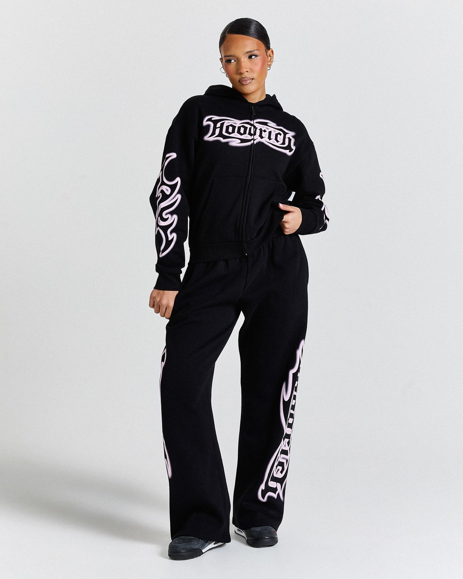 Person wearing a black tracksuit with white branding on a light gray background