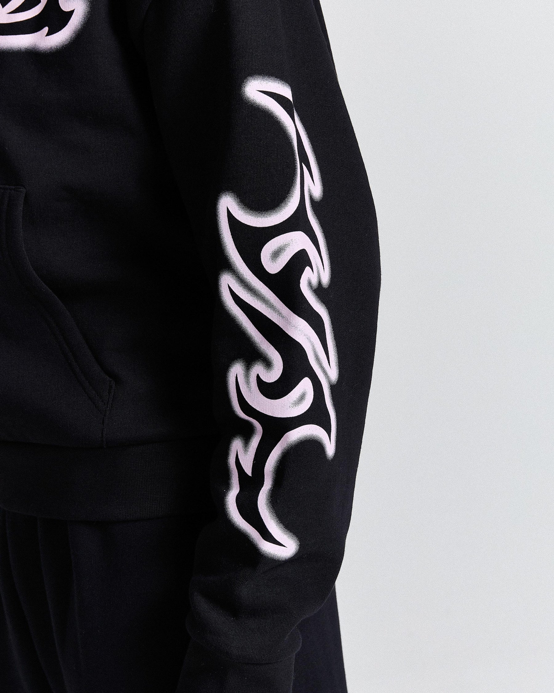 Black hoodie with white tribal designs on sleeves against a light gray background