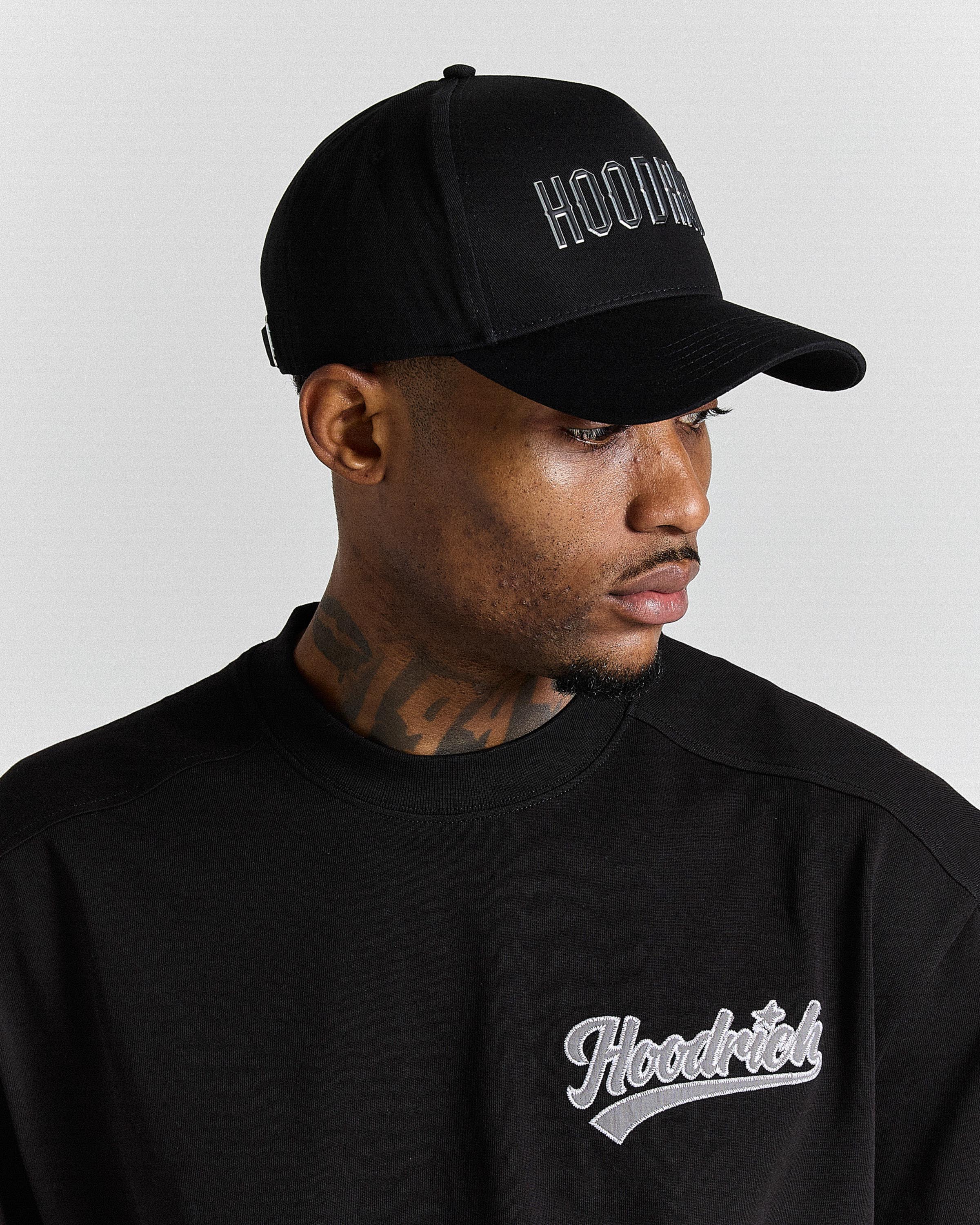 Man wearing a black cap and sweatshirt with 'Hoodrich' branding on a gray background