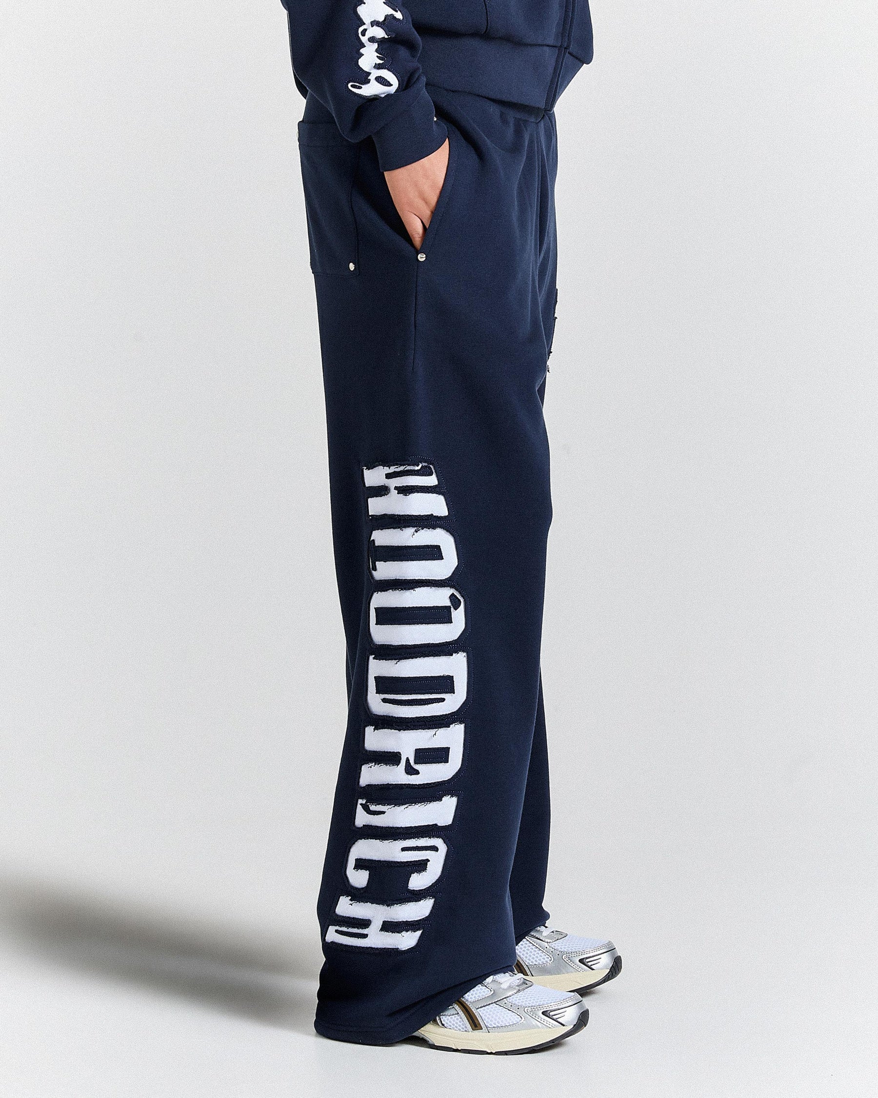 Navy blue sweatpants with white text on a light gray background