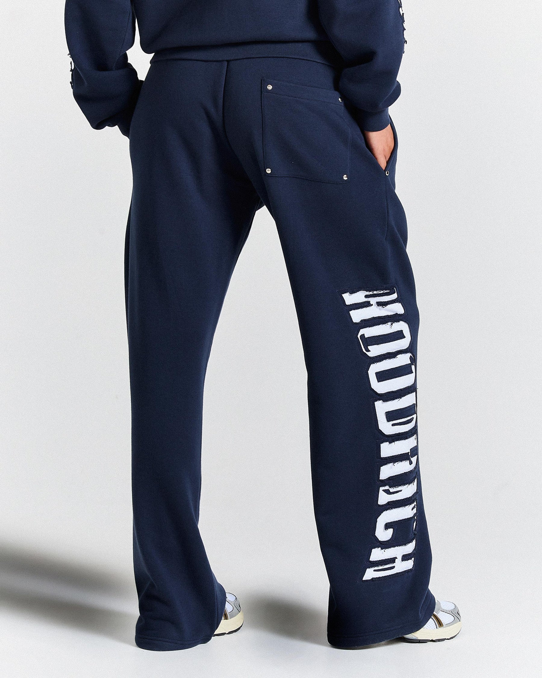 Navy blue sweatpants with 'Hoodrich' branding on a light gray background