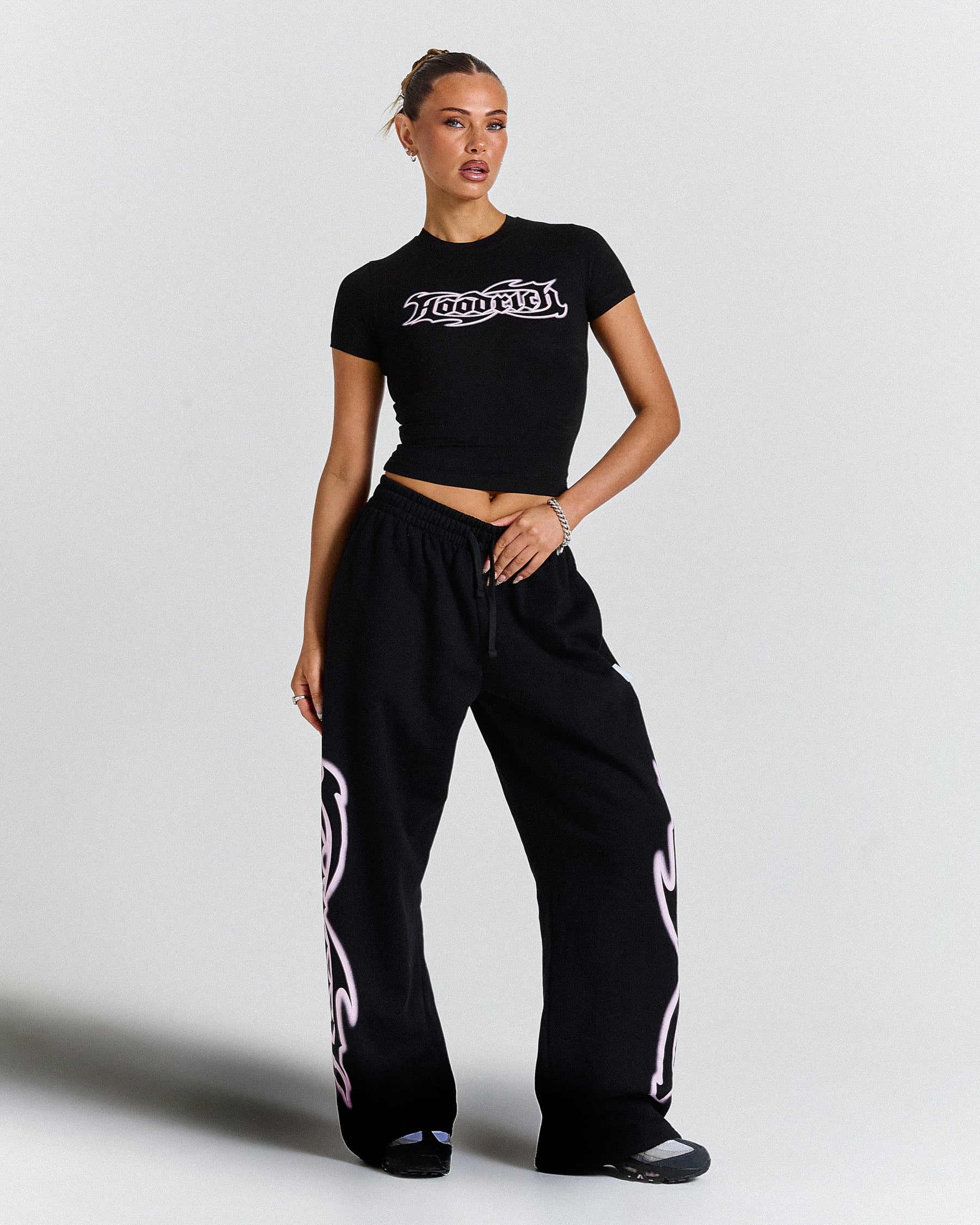 Woman wearing a black crop top and black pants with white text on a light gray background