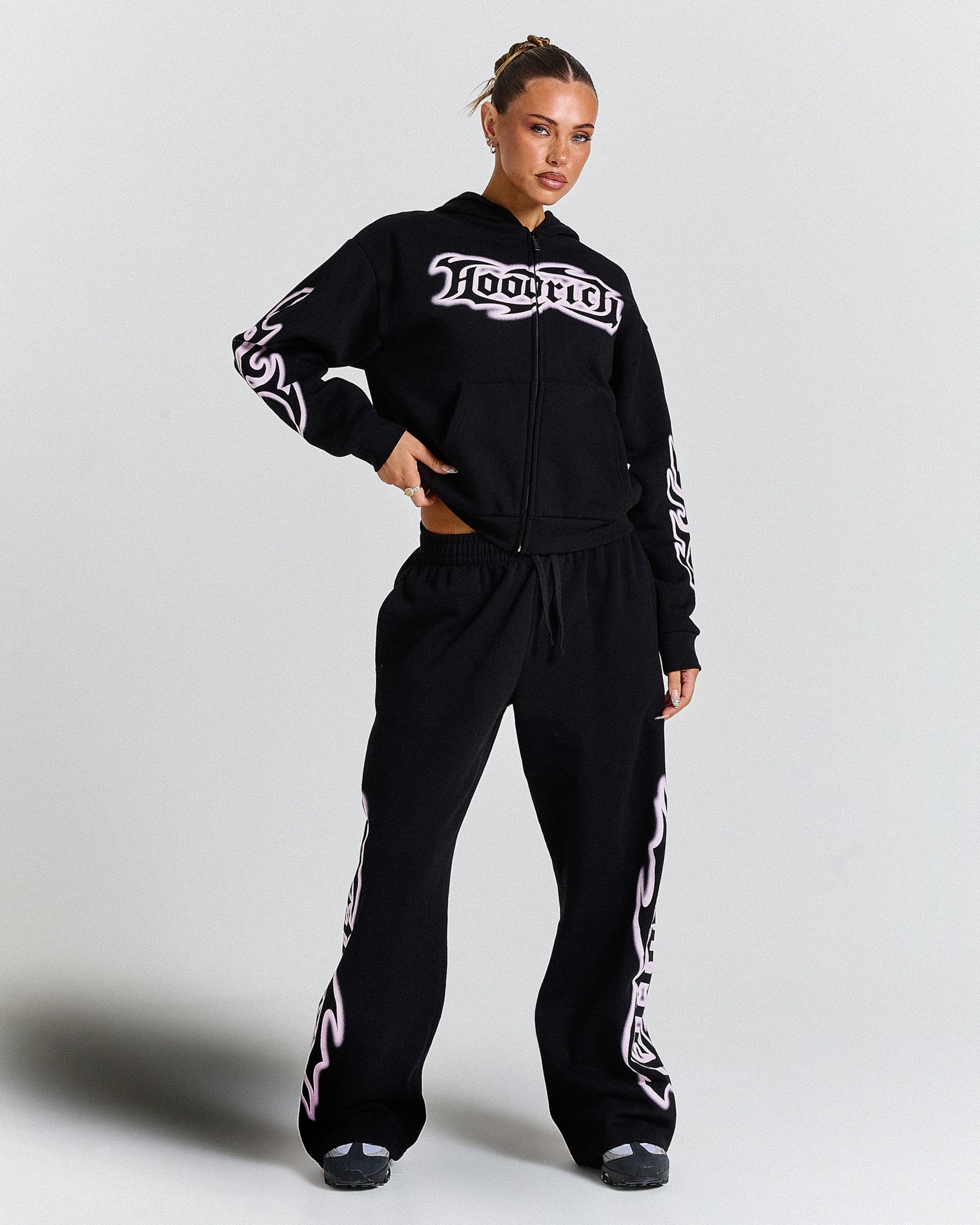 Person wearing a black tracksuit with white branding on a light gray background