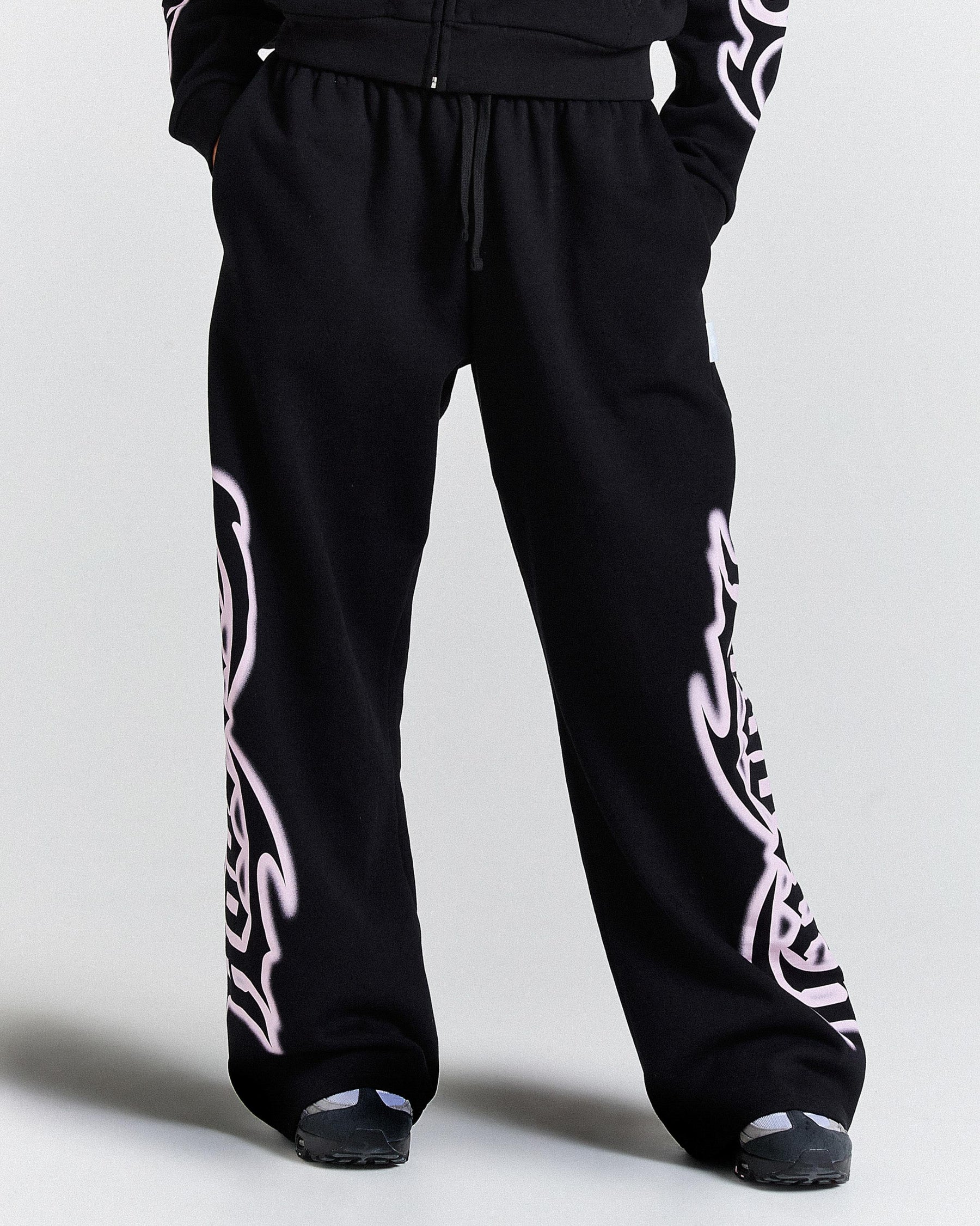Black sweatpants with white tribal designs on a light gray background