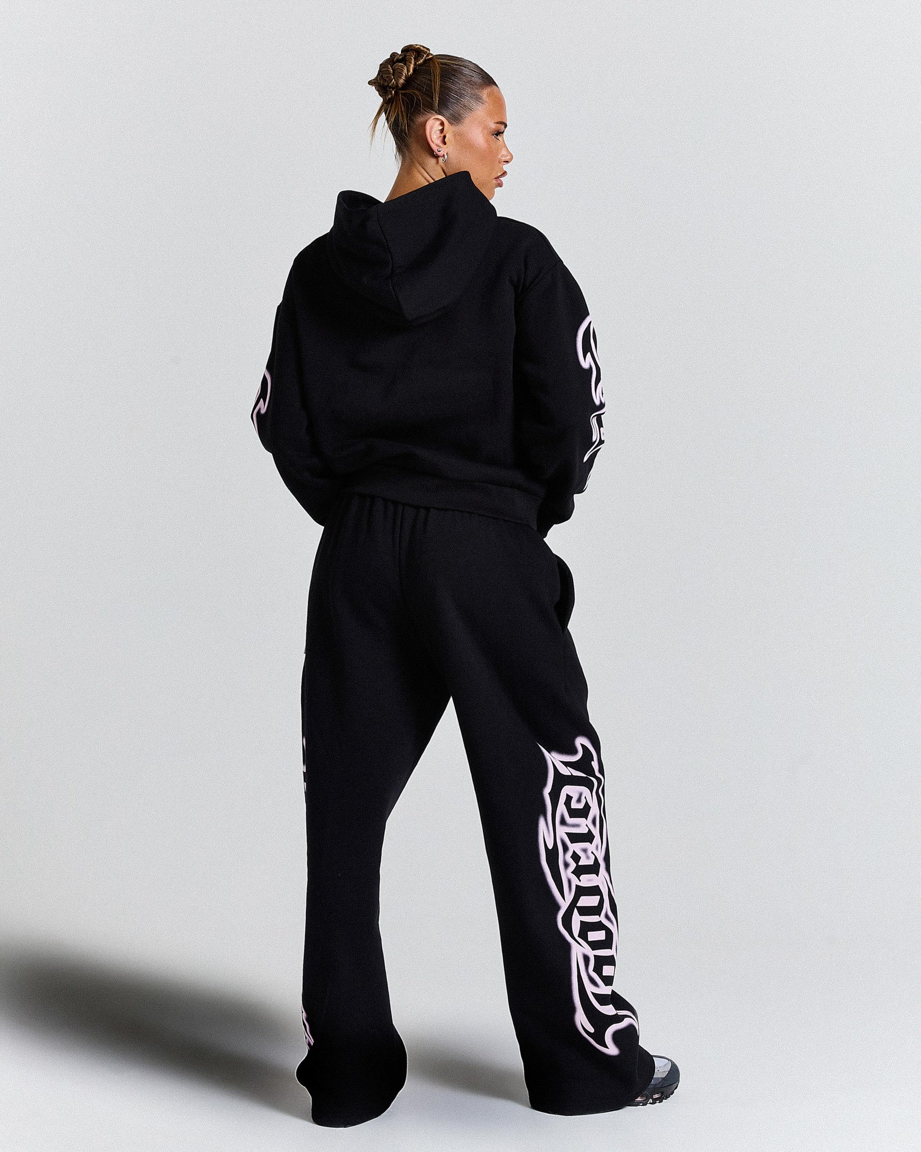 Person wearing a black tracksuit with white designs on a light gray background