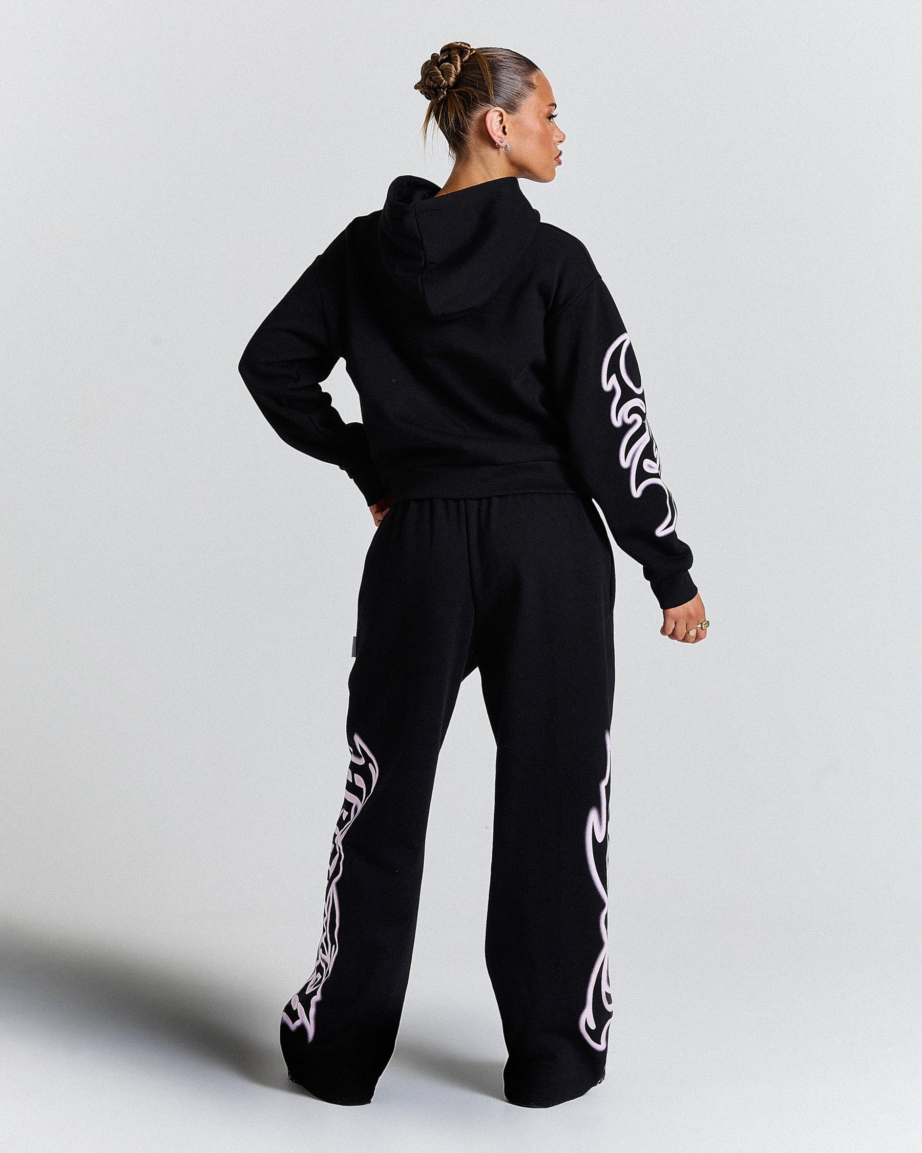 Person wearing a black tracksuit with white patterns on a light gray background