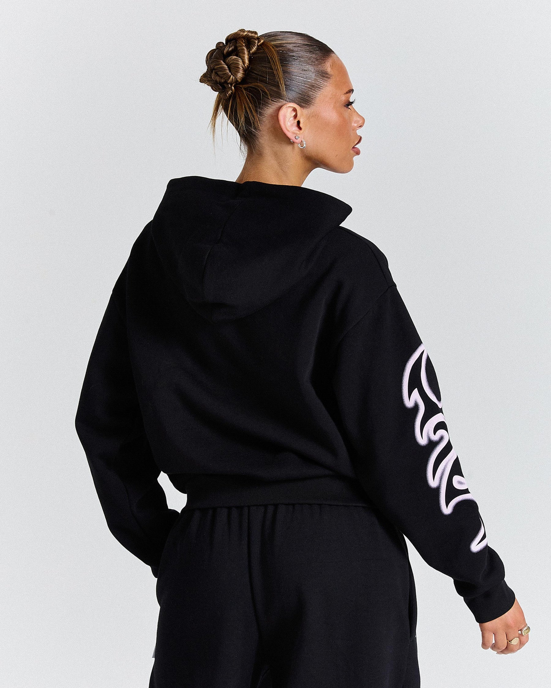 Person wearing a black hoodie with white text on sleeves against a light gray background