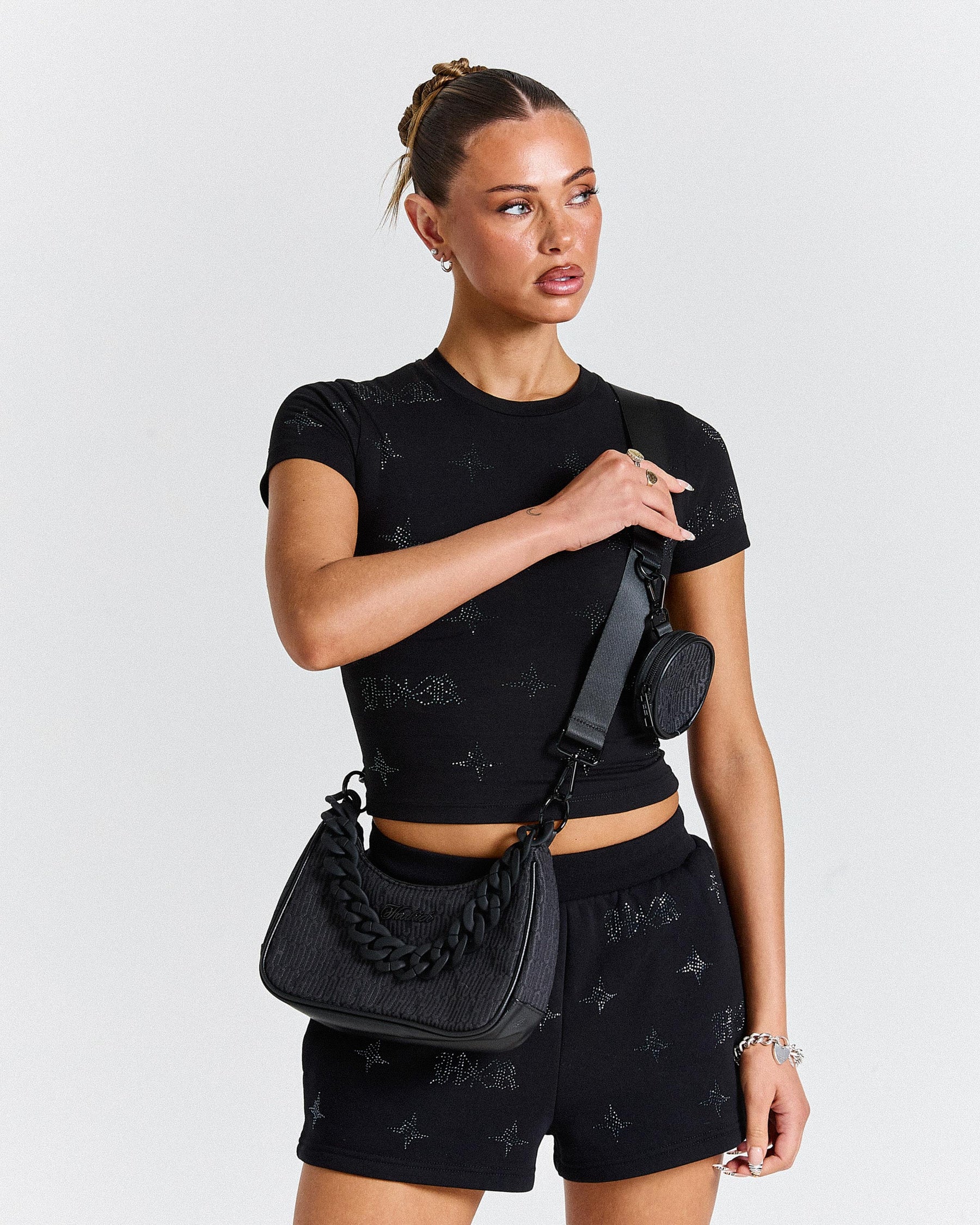 Woman wearing a black outfit with matching accessories on a plain background