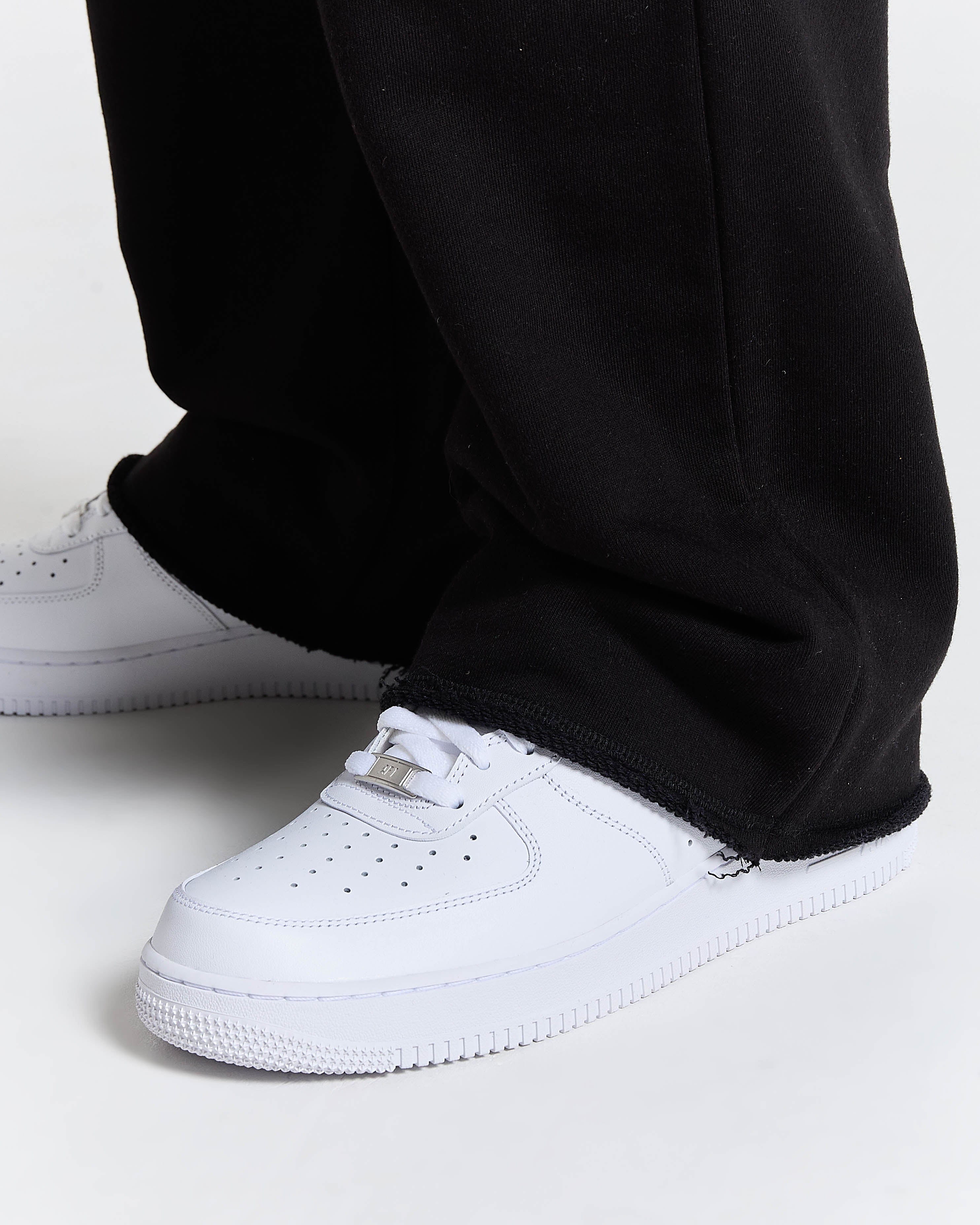 White sneakers with black pants on a white background