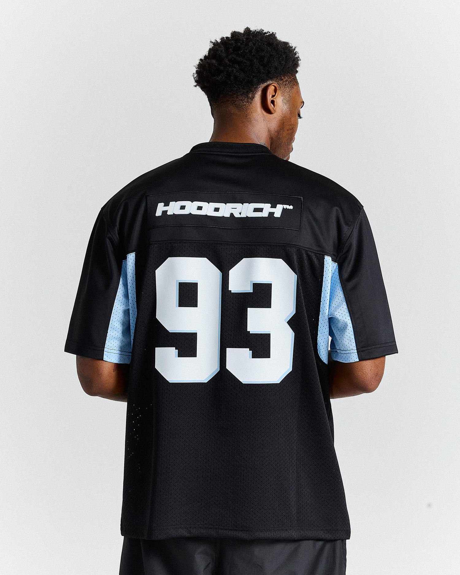 Person wearing a black sports jersey with 'Hoodrich' and number '93' on the back against a white background